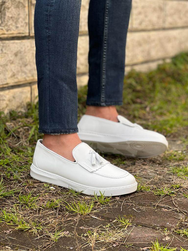Close-up view of white tassel leather loafers with a lightweight EVA sole, photographed in bright lighting to highlight their sleek design and soft texture.