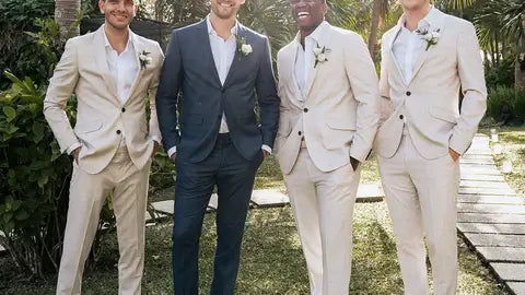 Groomsmen in matching lightweight beige summer suits with open-collar shirts, standing beside a groom in a navy wedding suit at an outdoor tropical ceremony