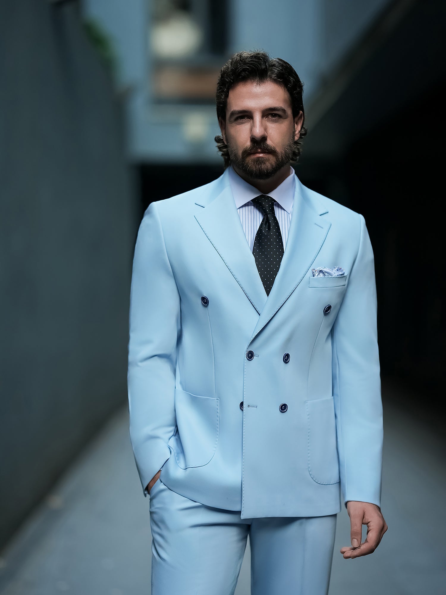 Men wearing a sky-blue double-breasted slim-fit suit with a white shirt and black tie, styled in a modern indoor setting.