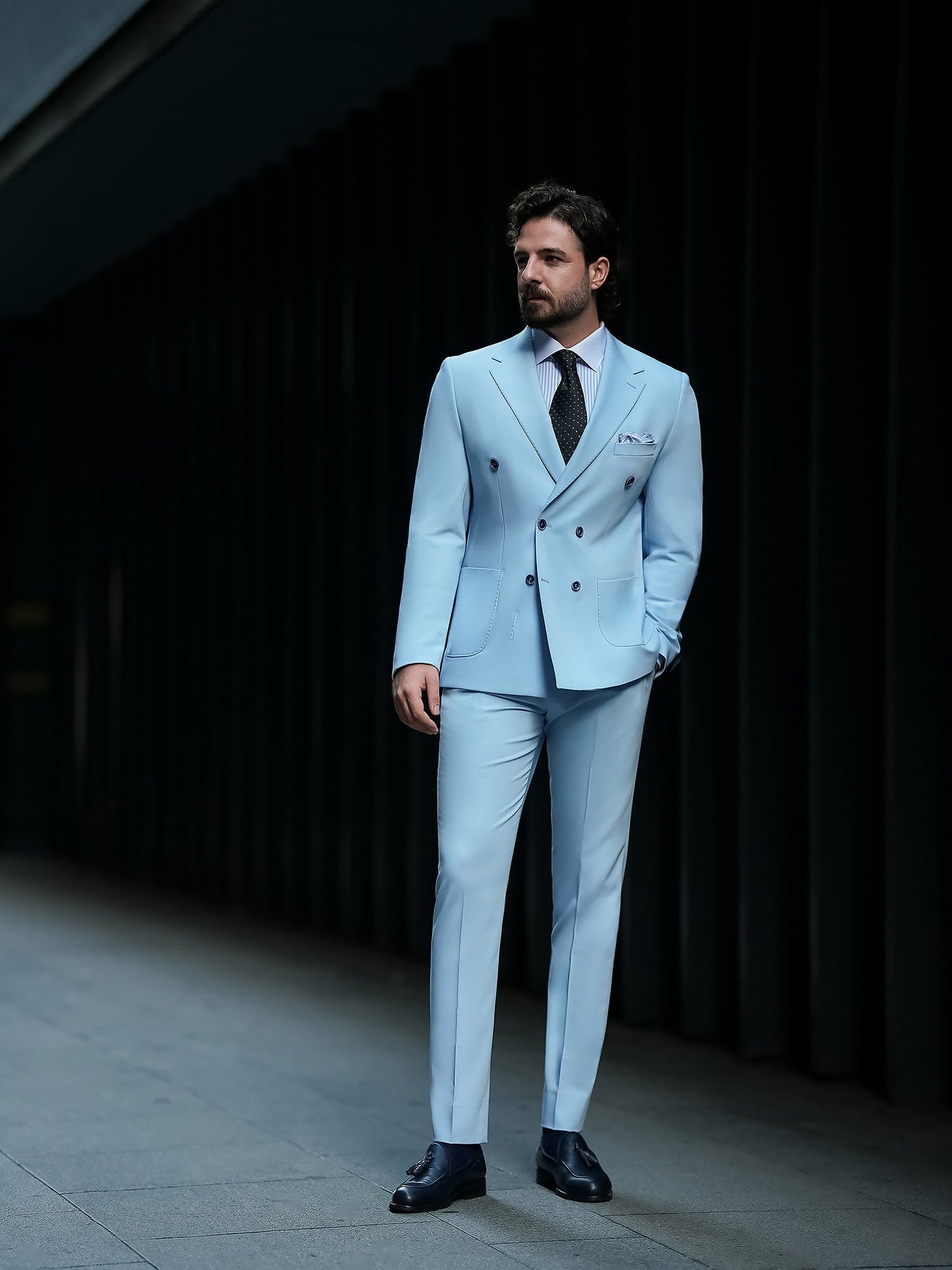 Men wearing a sky-blue double-breasted slim-fit suit with a white shirt and black tie, styled in a modern indoor setting.