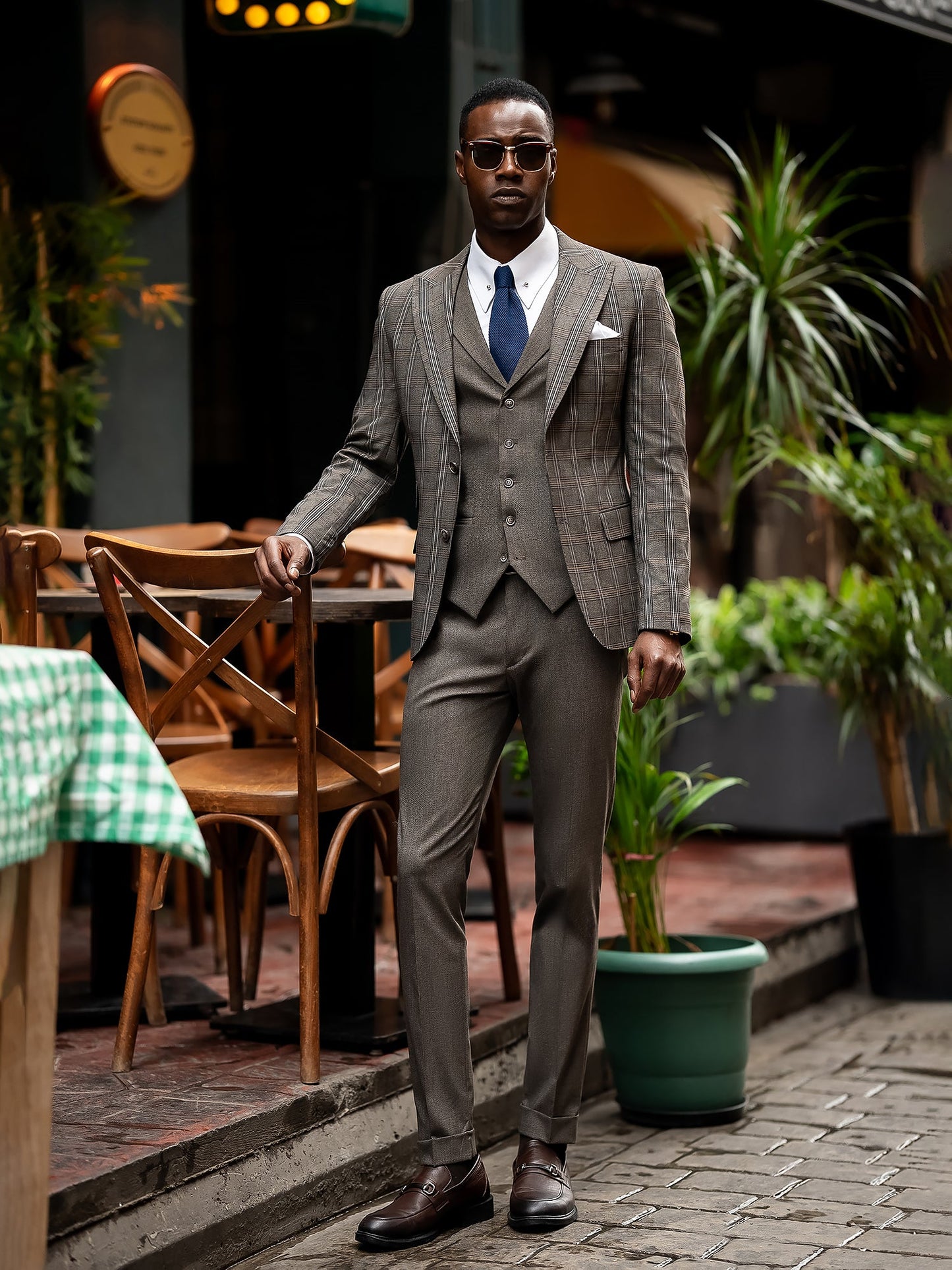 Men’s brown plaid slim-fit 3-piece suit with peak lapel blazer, matching vest and trousers, styled for formal and smart occasions with a modern tailored silhouette.