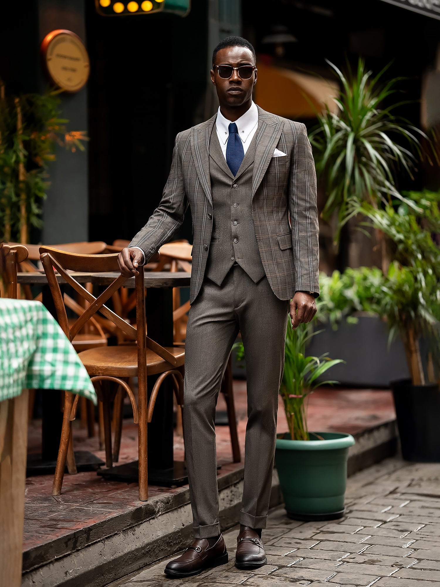 Men’s brown plaid slim-fit 3-piece suit with peak lapel blazer, matching vest and trousers, styled for formal and smart occasions with a modern tailored silhouette.