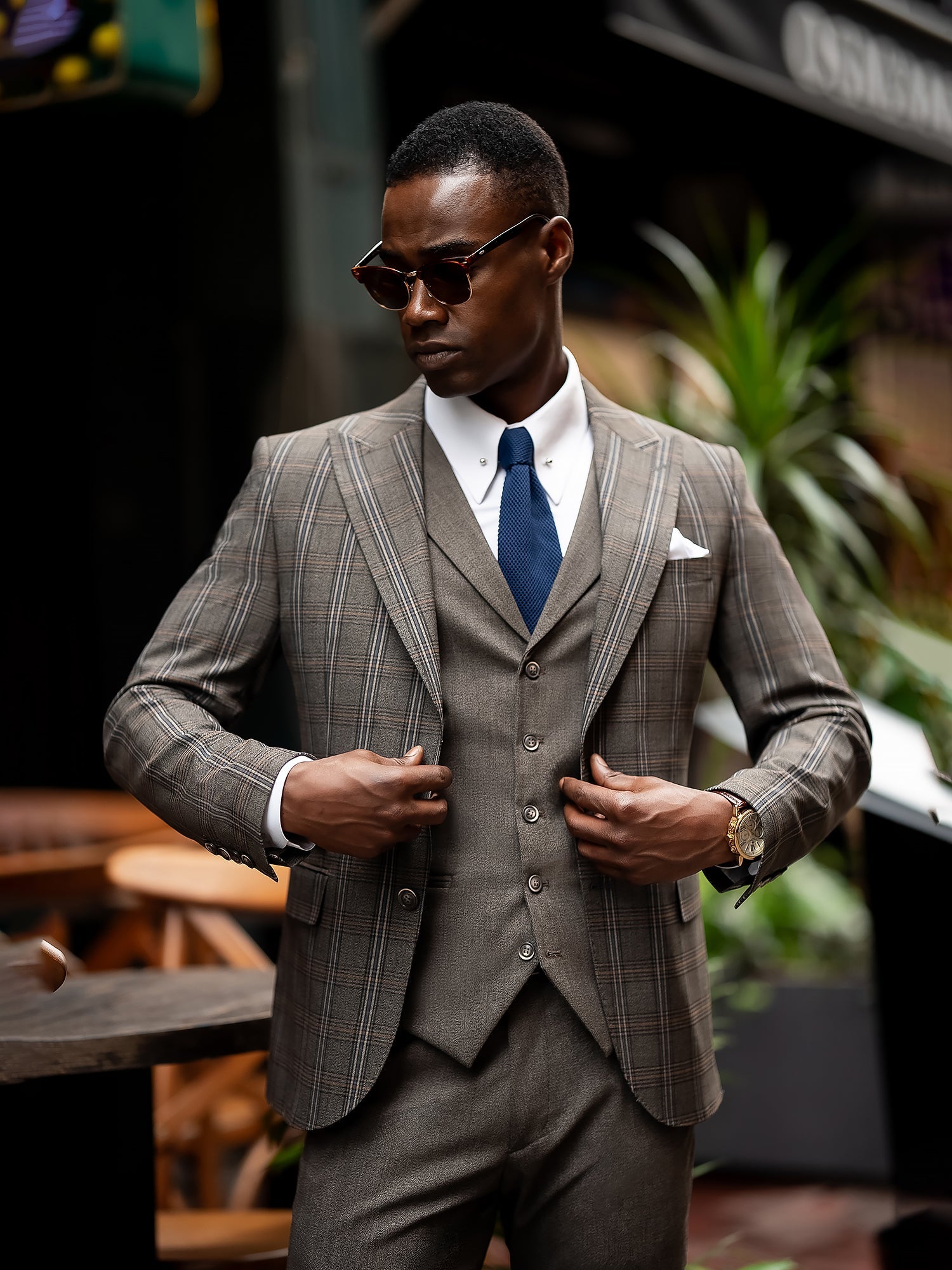 Men’s brown plaid slim-fit 3-piece suit with peak lapel blazer, matching vest and trousers, styled for formal and smart occasions with a modern tailored silhouette.