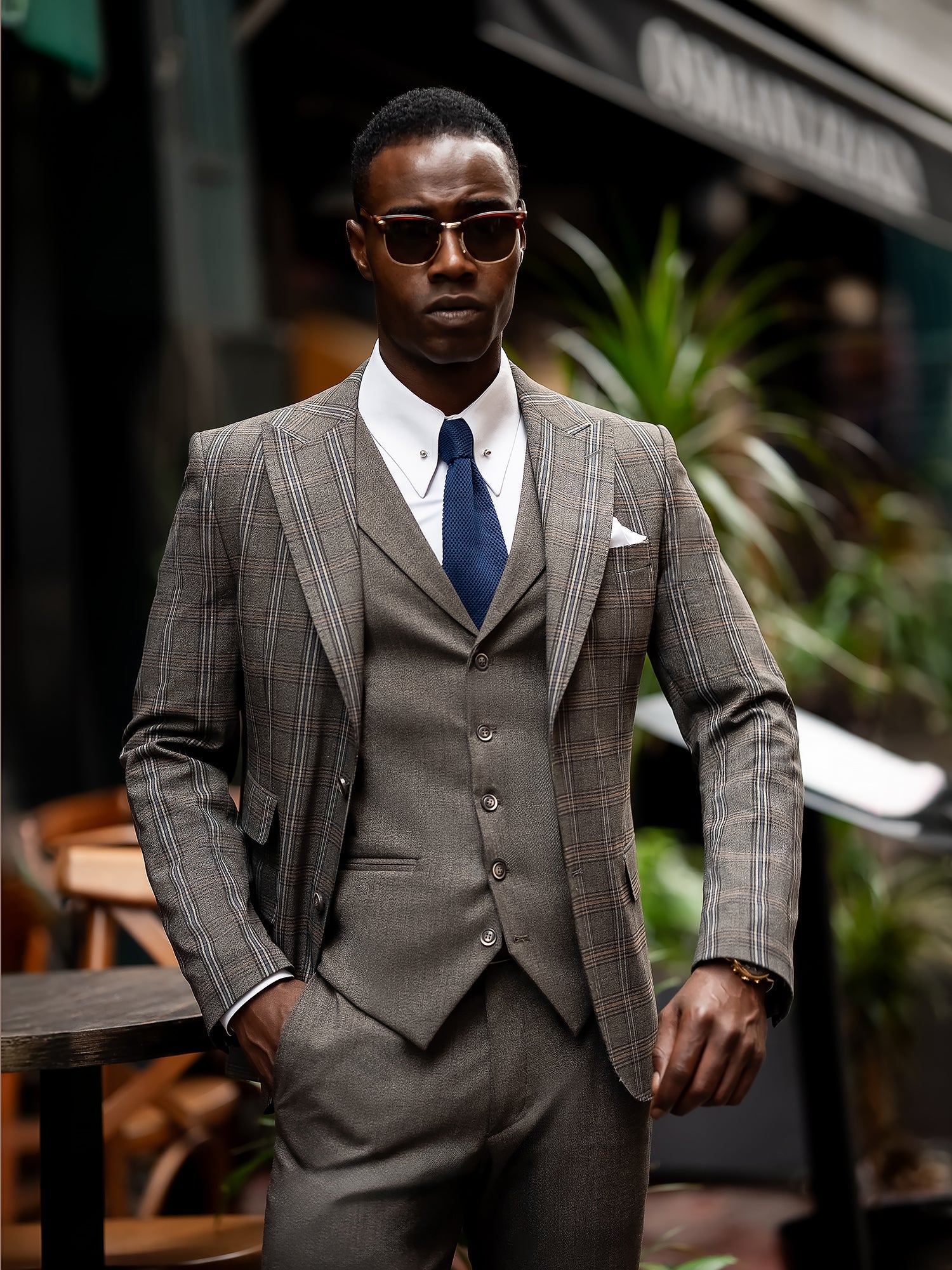 Men’s brown plaid slim-fit 3-piece suit with peak lapel blazer, matching vest and trousers, styled for formal and smart occasions with a modern tailored silhouette.