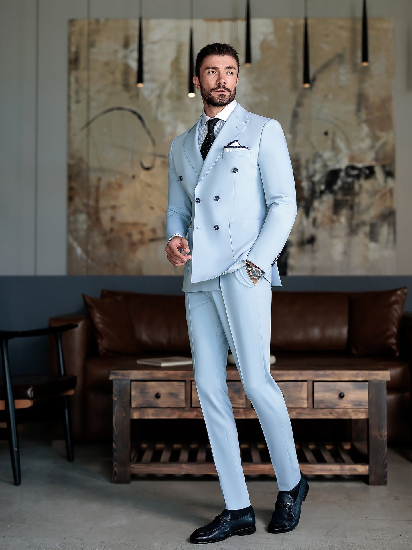 Men wearing a sky-blue double-breasted slim-fit suit with a white shirt and black tie, styled in a modern indoor setting.