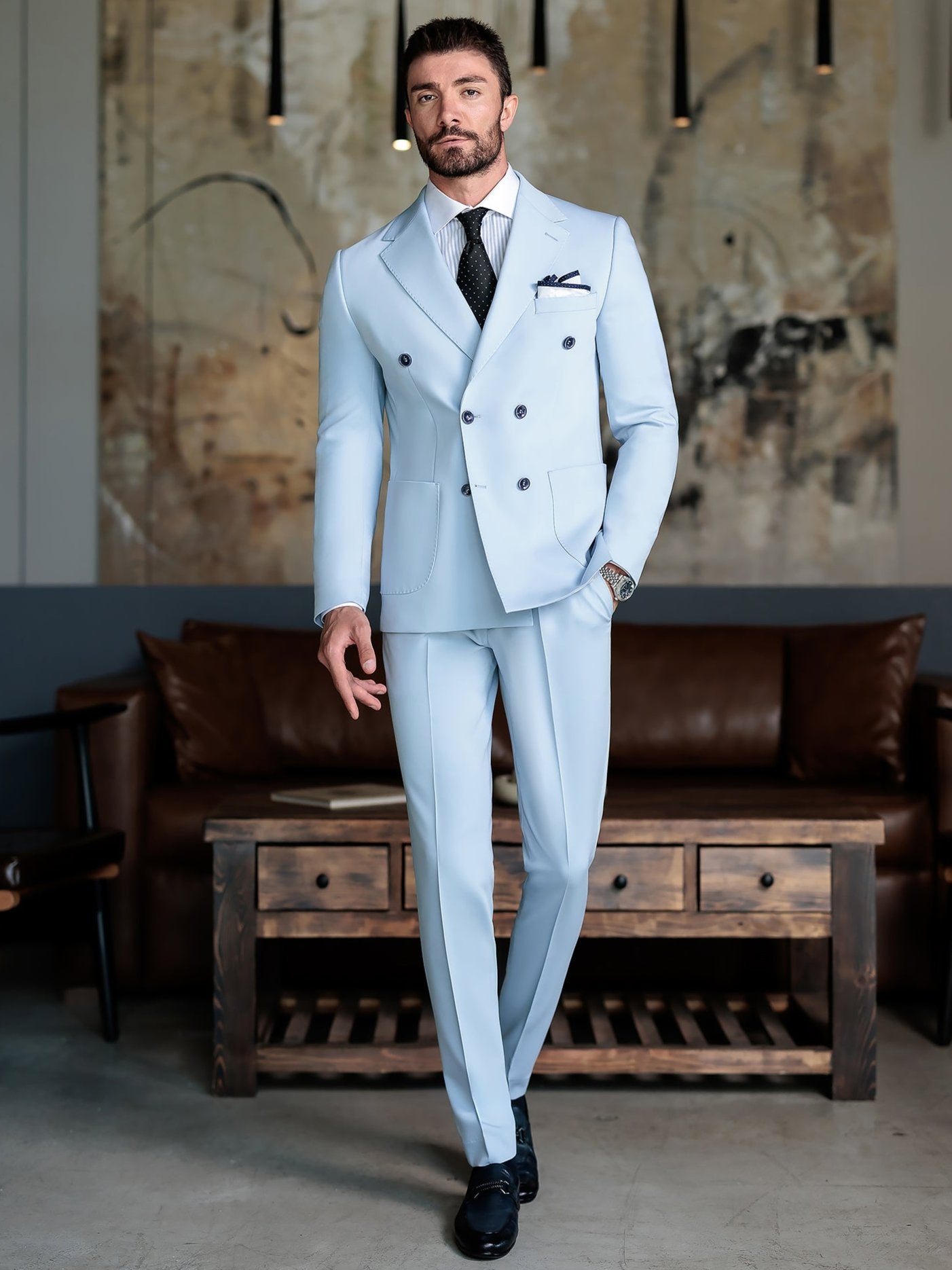 Men wearing a sky-blue double-breasted slim-fit suit with a white shirt and black tie, styled in a modern indoor setting.