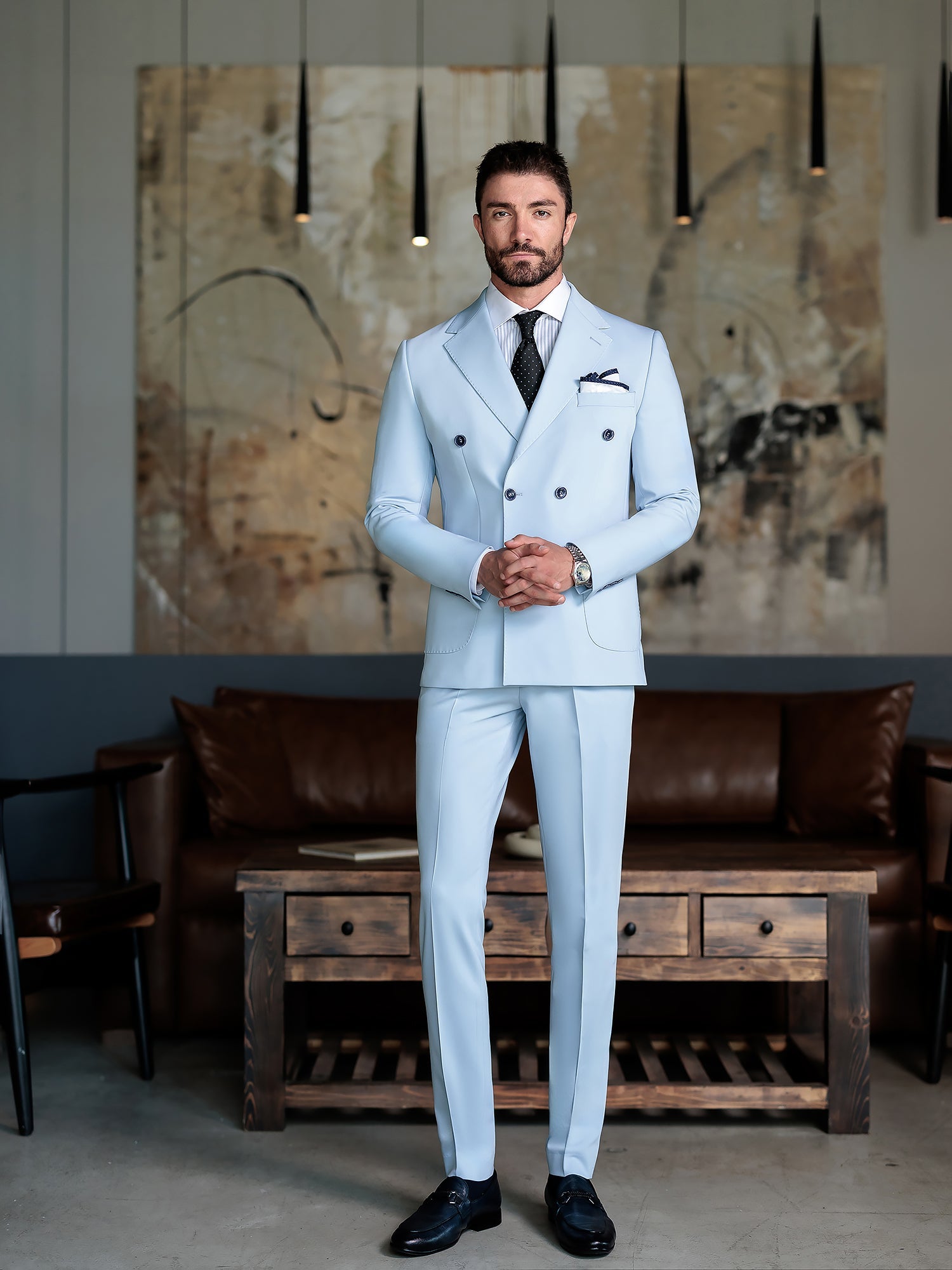 Men wearing a sky-blue double-breasted slim-fit suit with a white shirt and black tie, styled in a modern indoor setting.