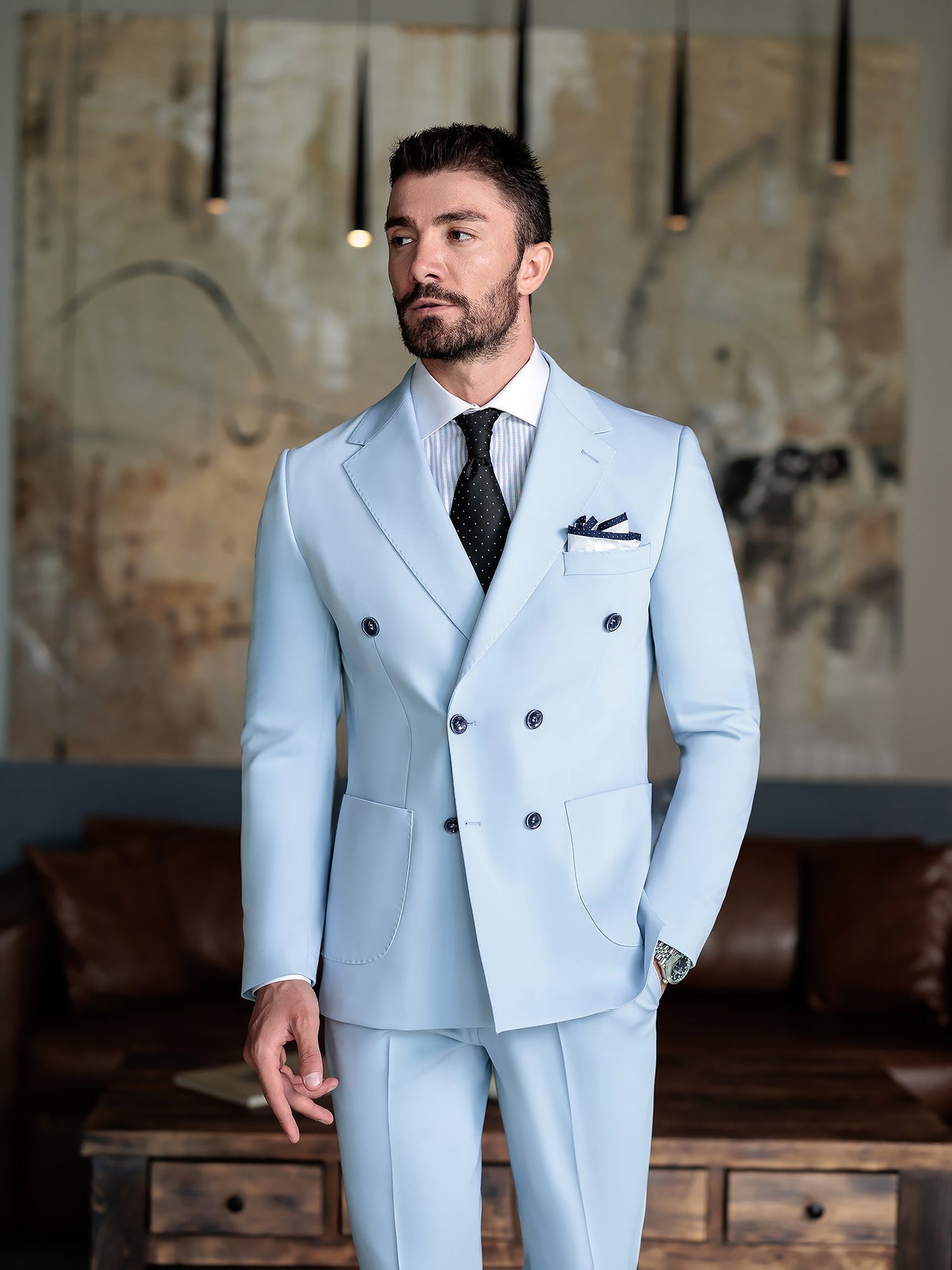 Men wearing a sky-blue double-breasted slim-fit suit with a white shirt and black tie, styled in a modern indoor setting.