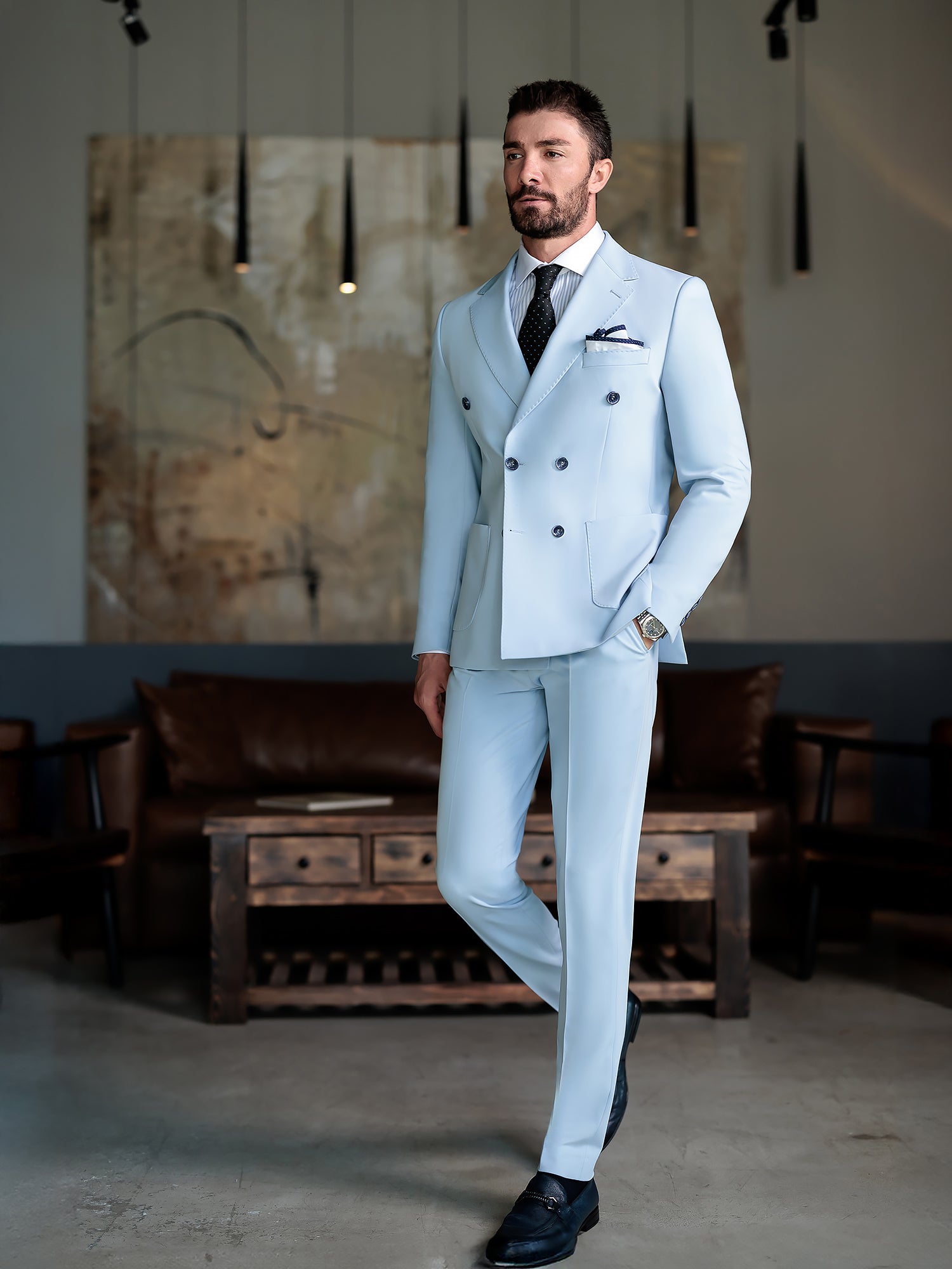 Men wearing a sky-blue double-breasted slim-fit suit with a white shirt and black tie, styled in a modern indoor setting.