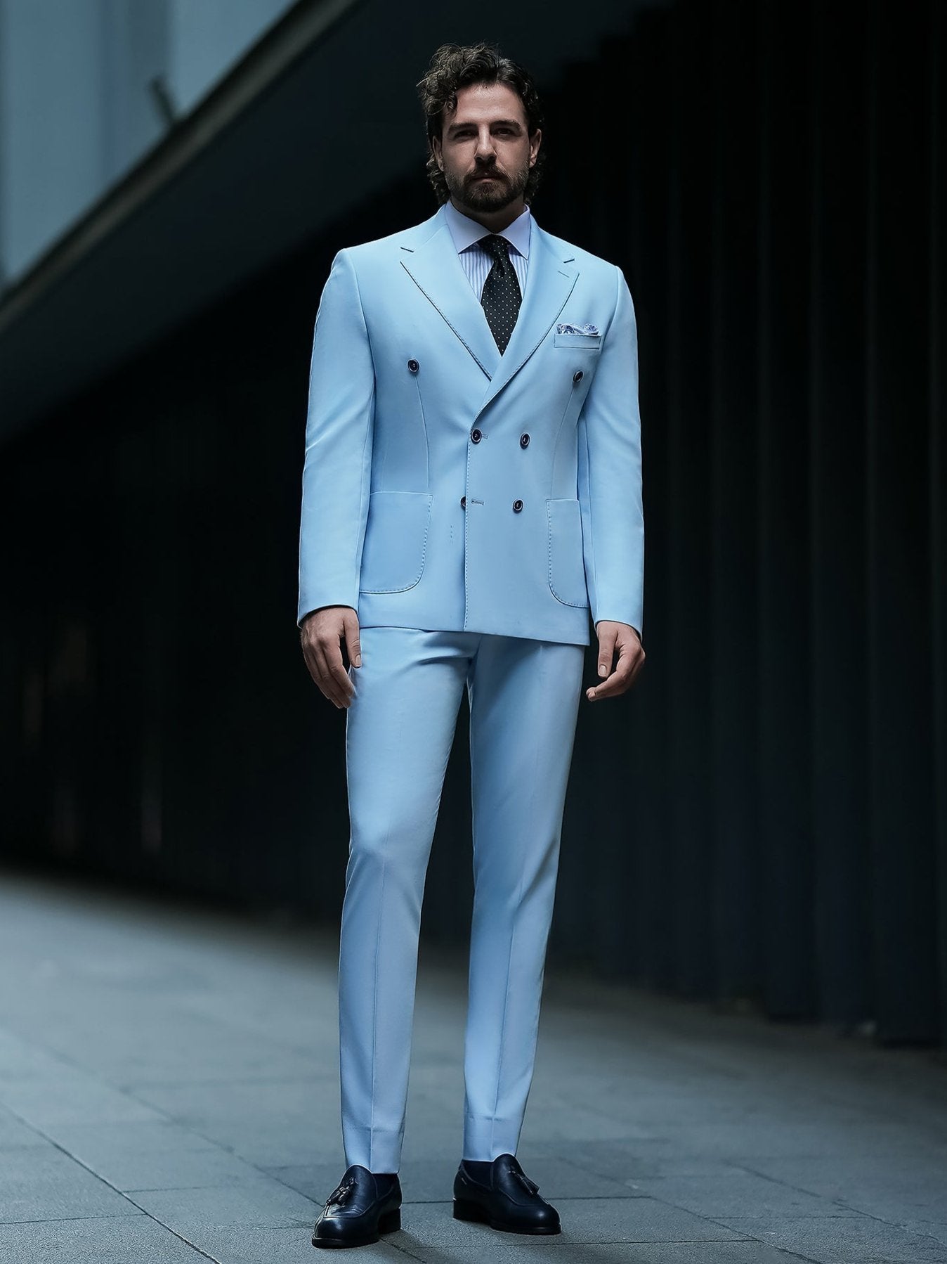 Men wearing a sky-blue double-breasted slim-fit suit with a white shirt and black tie, styled in a modern indoor setting.