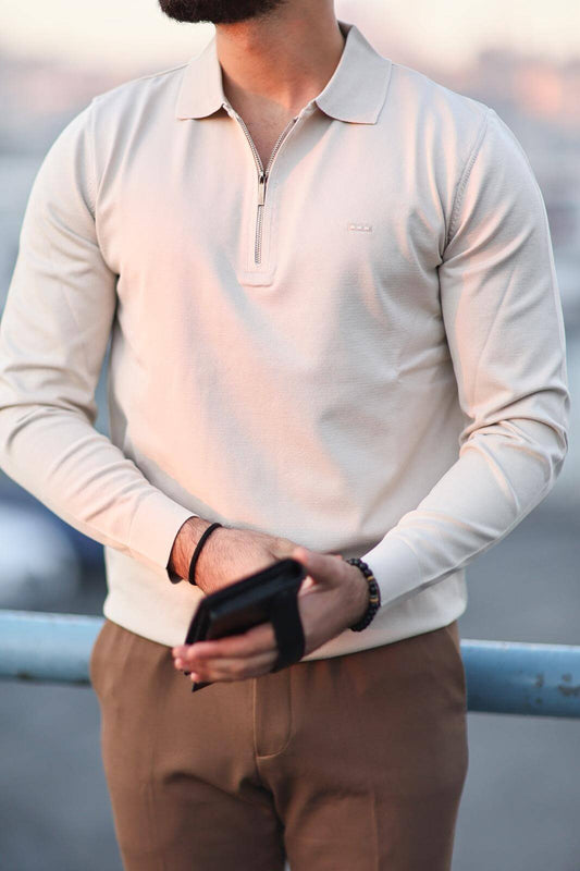 Men’s beige quarter-zip long sleeve polo shirt worn with camel trousers in an outdoor setting