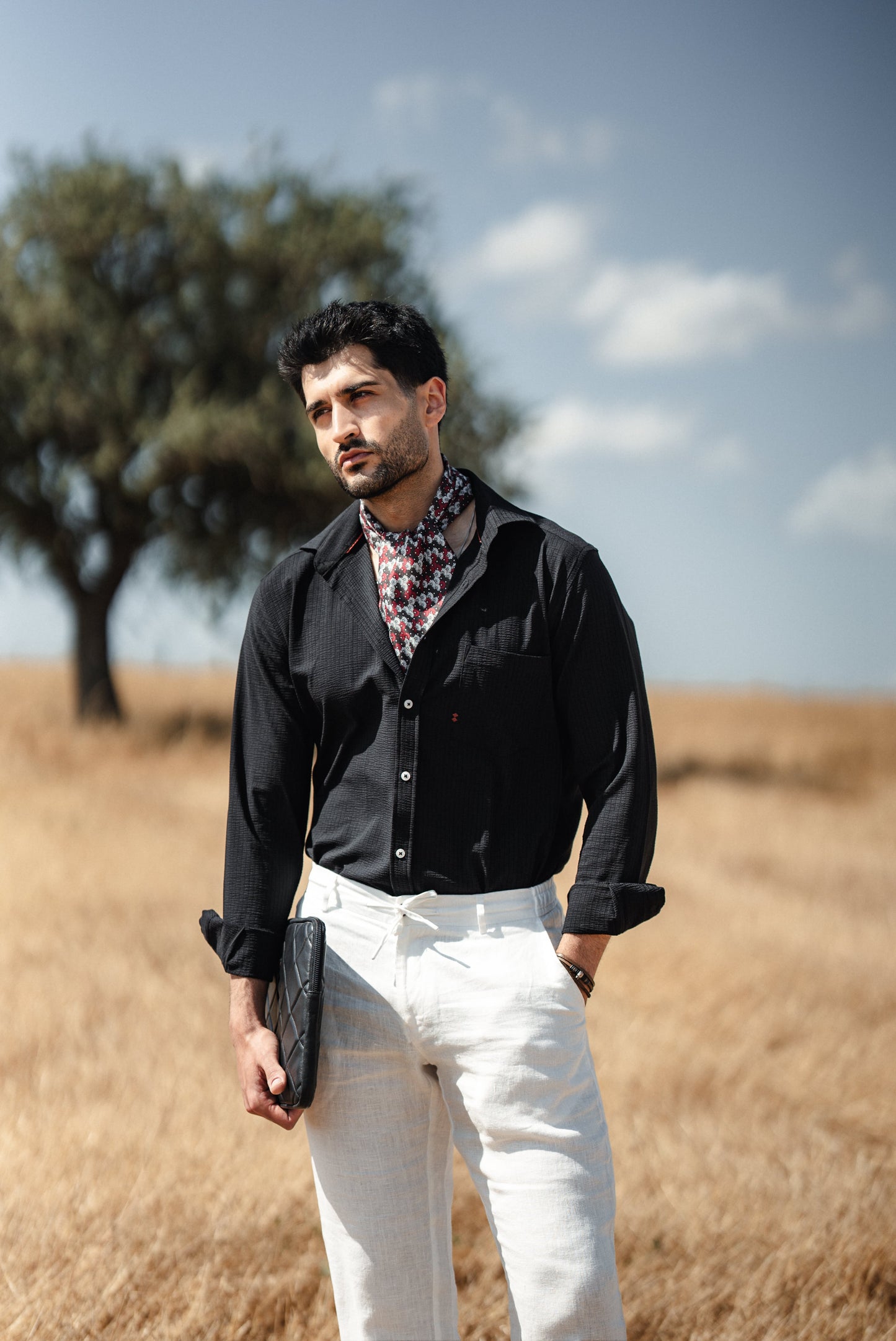 Man wearing a black linen button-down slim fit shirt, paired with chinos and loafers, exuding summer elegance on a Mediterranean terrace.