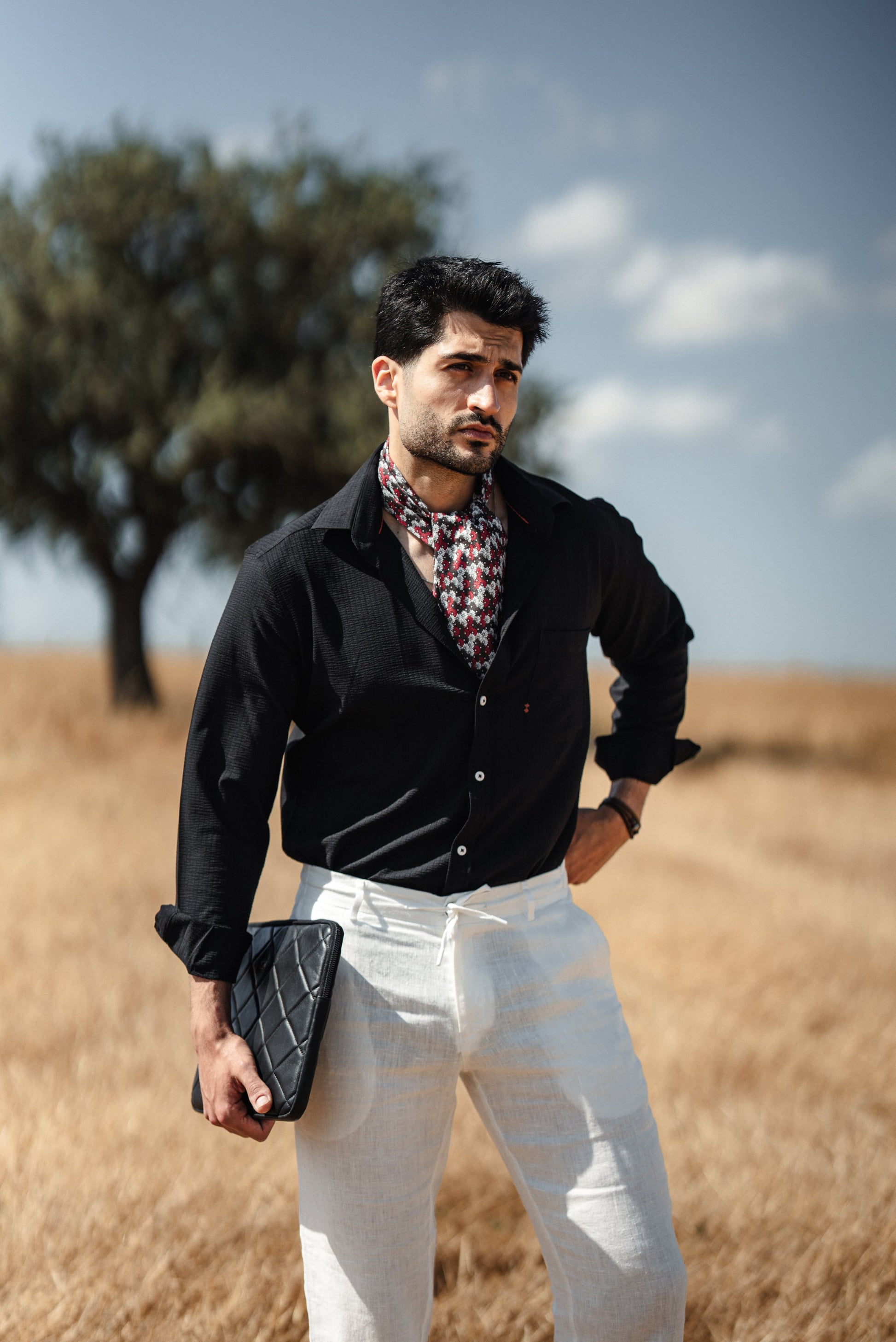 Man wearing a black linen button-down slim fit shirt, paired with chinos and loafers, exuding summer elegance on a Mediterranean terrace.