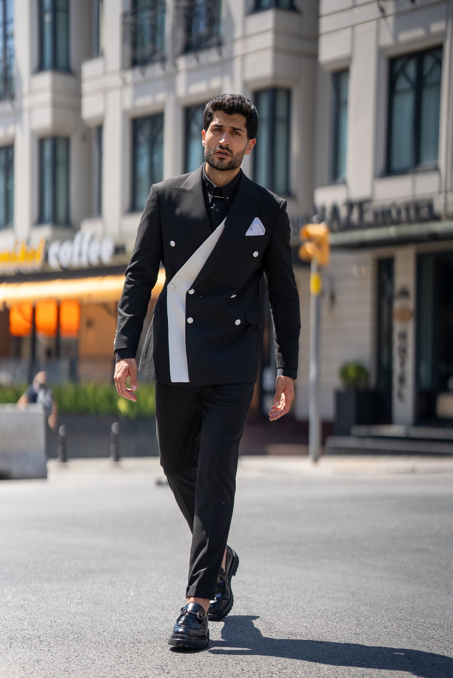 Man wearing a St. Tropez Black Slim Fit Double-Breasted Suit, styled with a white shirt and loafers, set against a luxurious coastal backdrop.