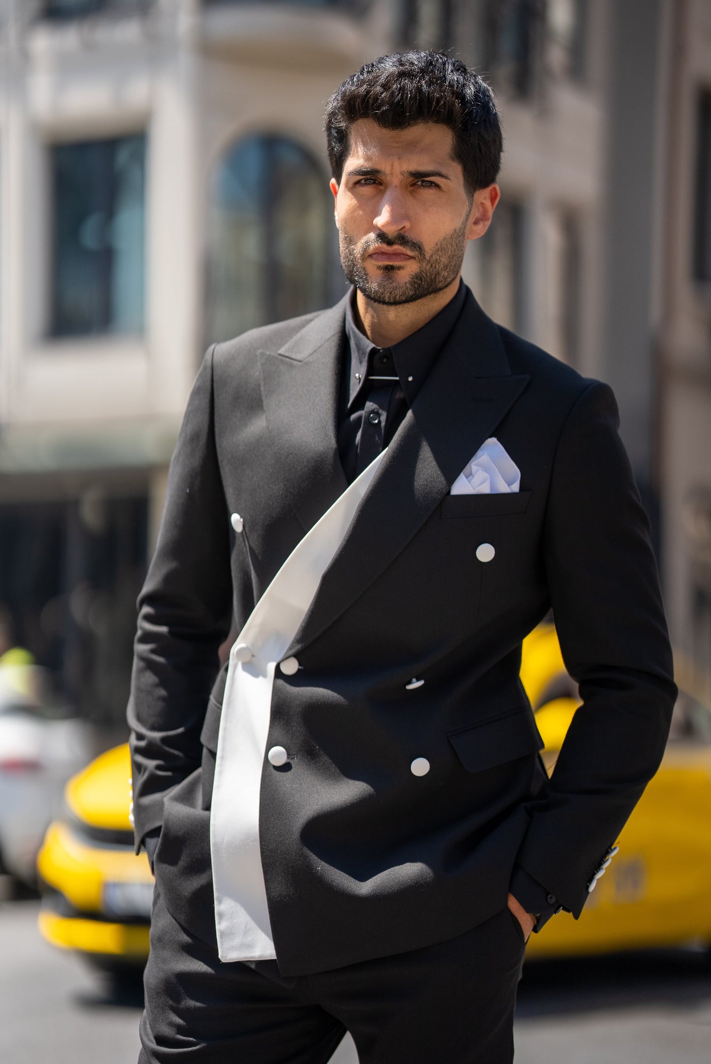 Man wearing a St. Tropez Black Slim Fit Double-Breasted Suit, styled with a white shirt and loafers, set against a luxurious coastal backdrop.