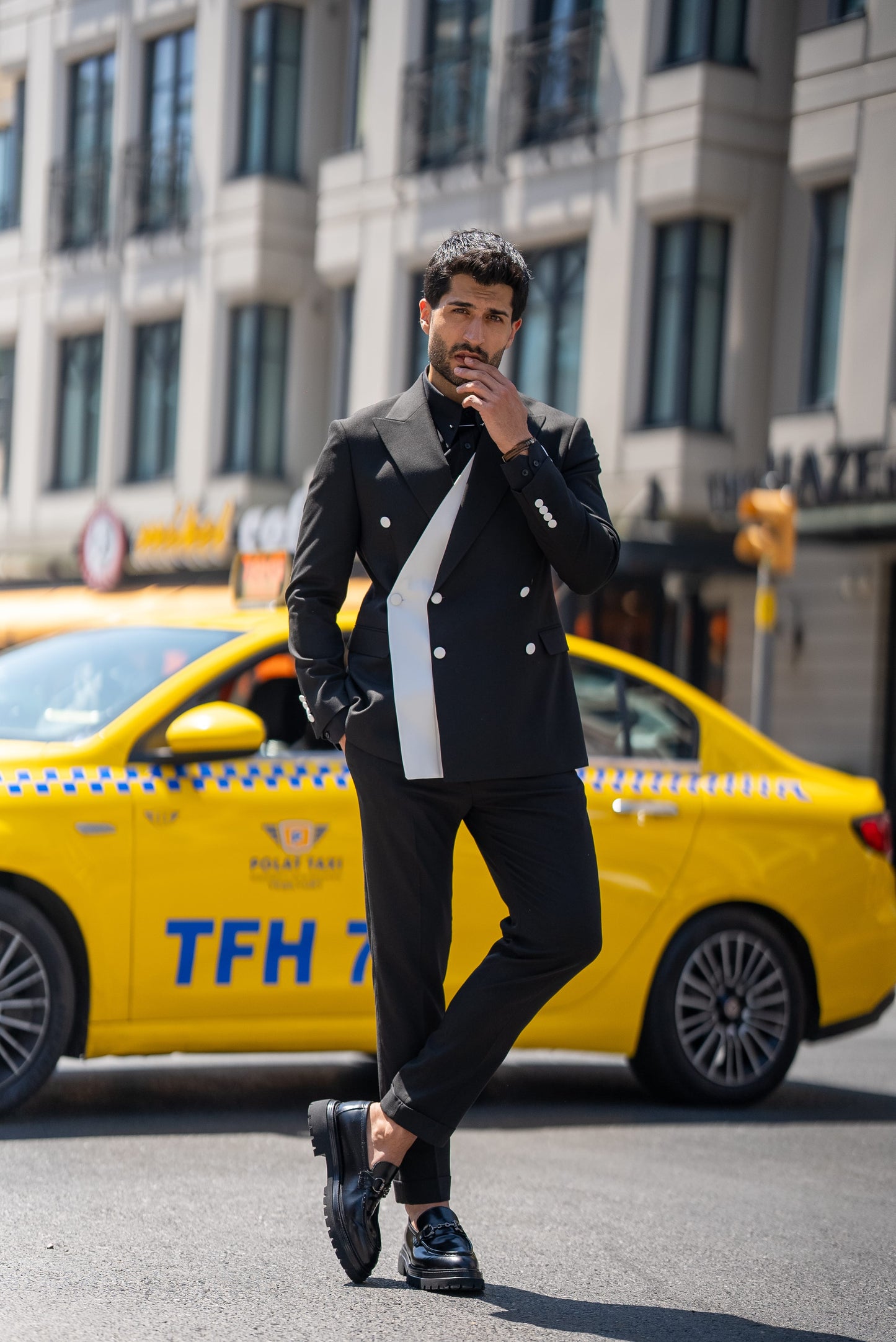 Man wearing a St. Tropez Black Slim Fit Double-Breasted Suit, styled with a white shirt and loafers, set against a luxurious coastal backdrop.