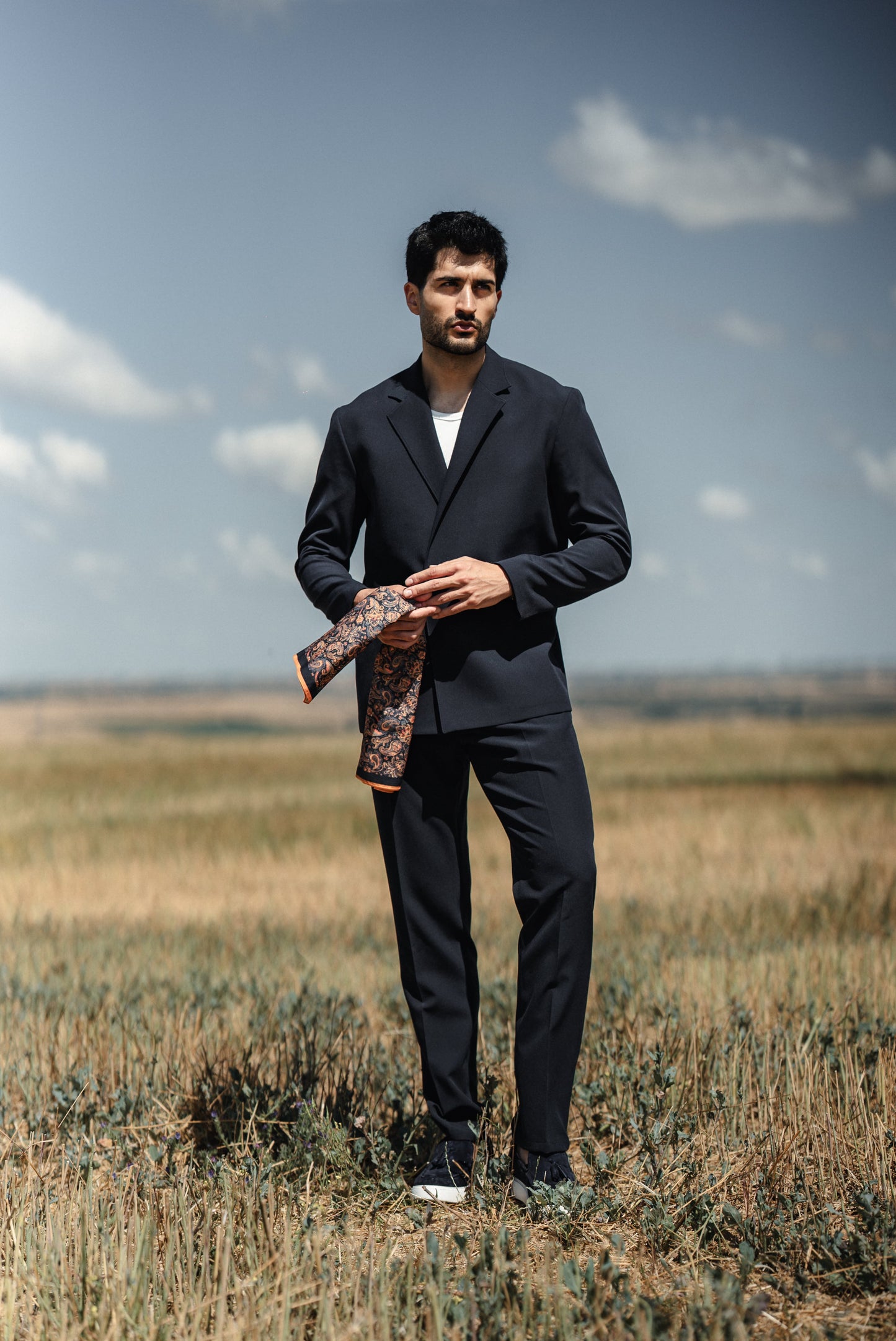 Man wearing HolloMen Cannes Navy Blue Lustrofin Blazer Suit, styled with a white shirt and navy blue loafers, set against an elegant outdoor urban backdrop.
