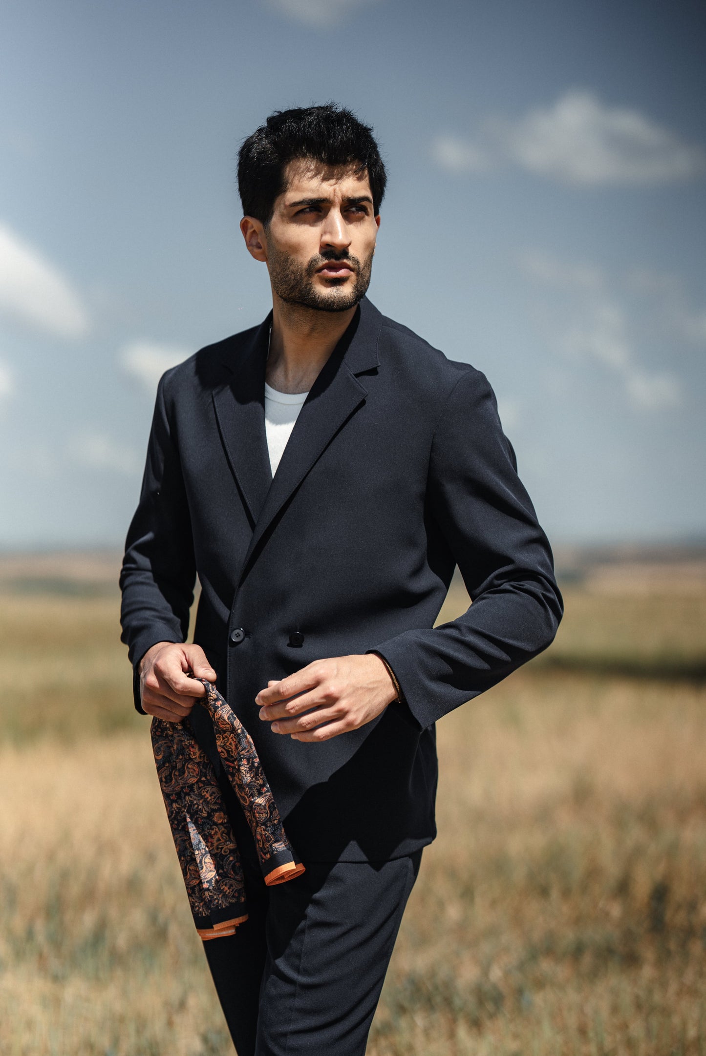 Man wearing HolloMen Cannes Navy Blue Lustrofin Blazer Suit, styled with a white shirt and navy blue loafers, set against an elegant outdoor urban backdrop.