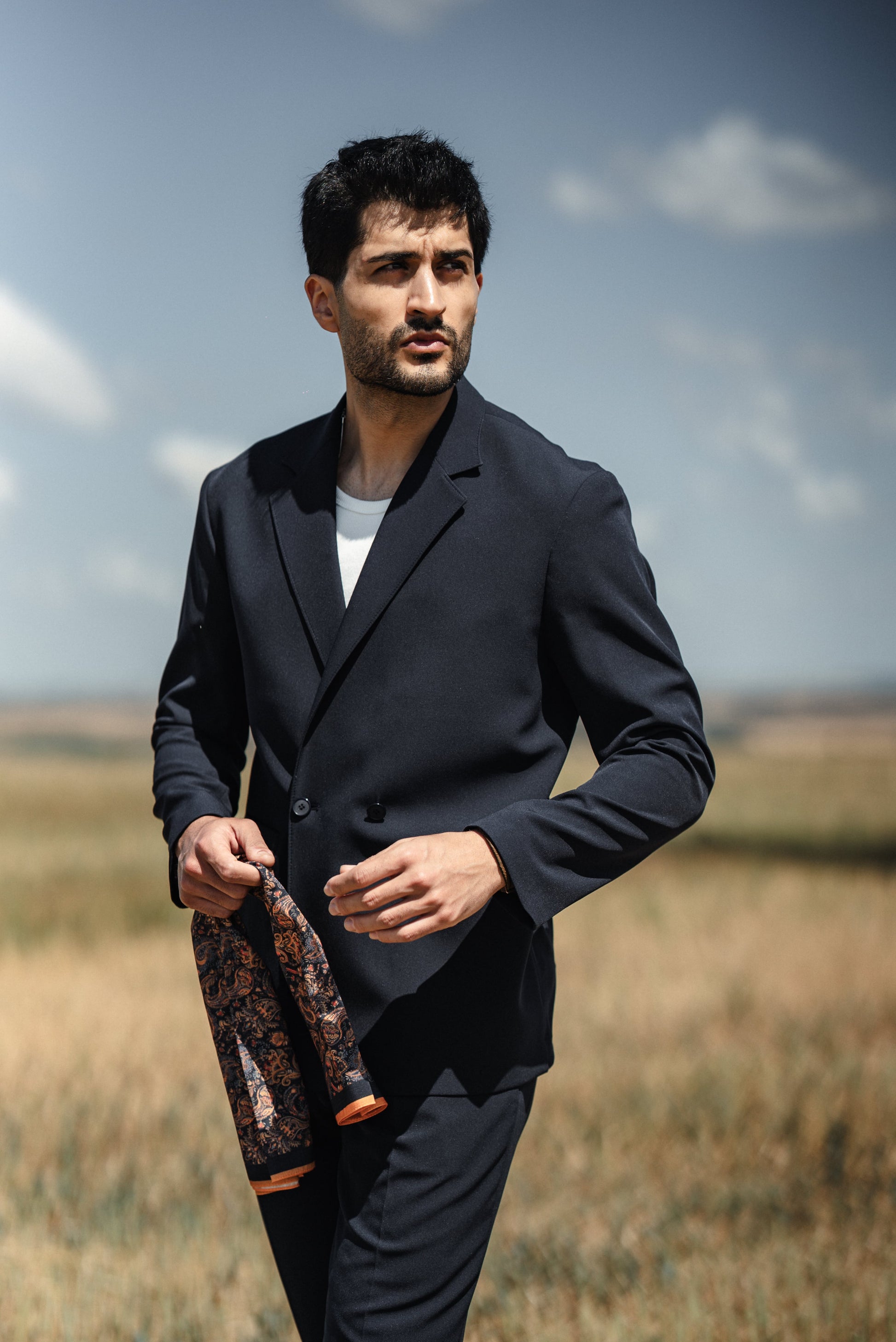 Man wearing HolloMen Cannes Navy Blue Lustrofin Blazer Suit, styled with a white shirt and navy blue loafers, set against an elegant outdoor urban backdrop.