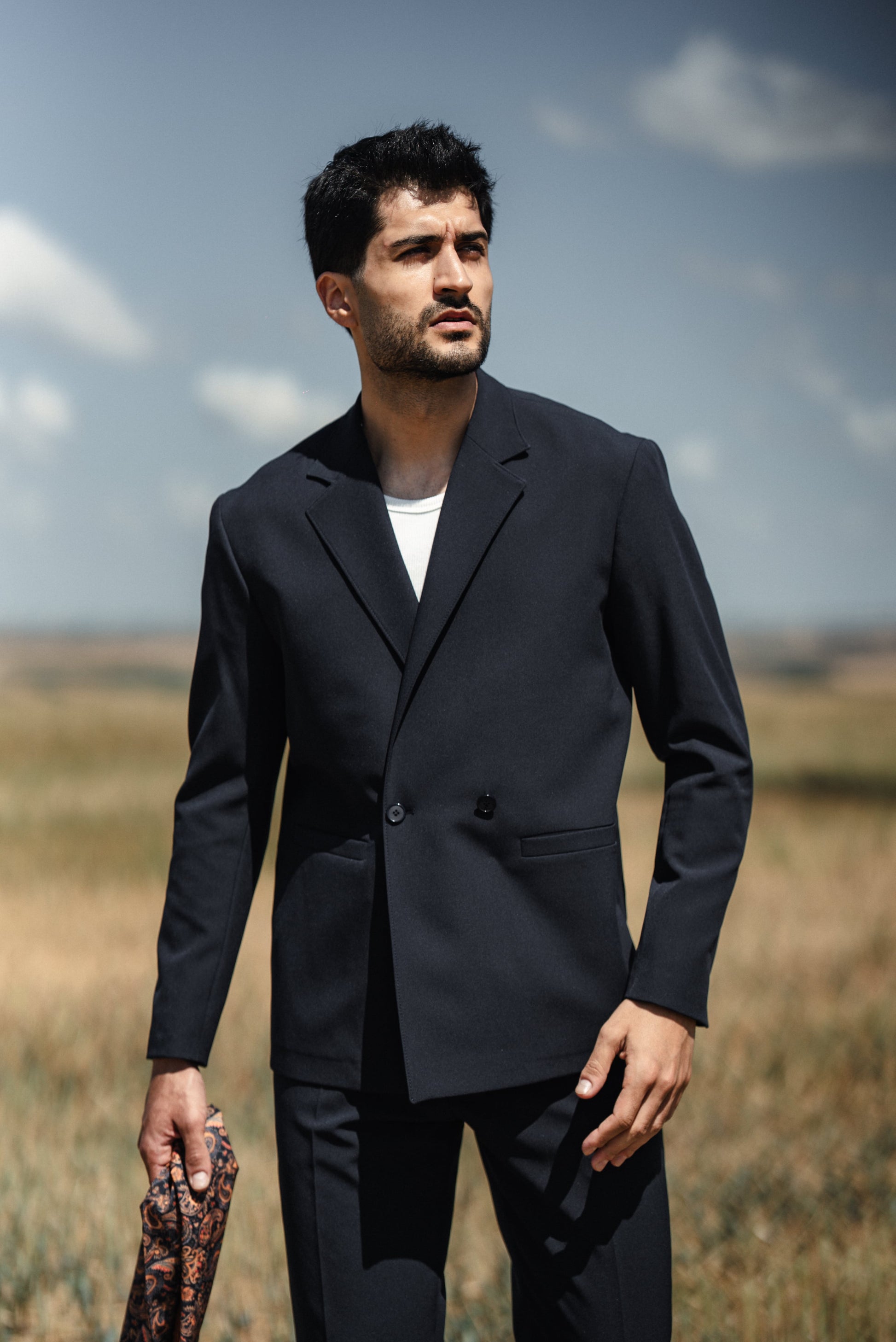 Man wearing HolloMen Cannes Navy Blue Lustrofin Blazer Suit, styled with a white shirt and navy blue loafers, set against an elegant outdoor urban backdrop.