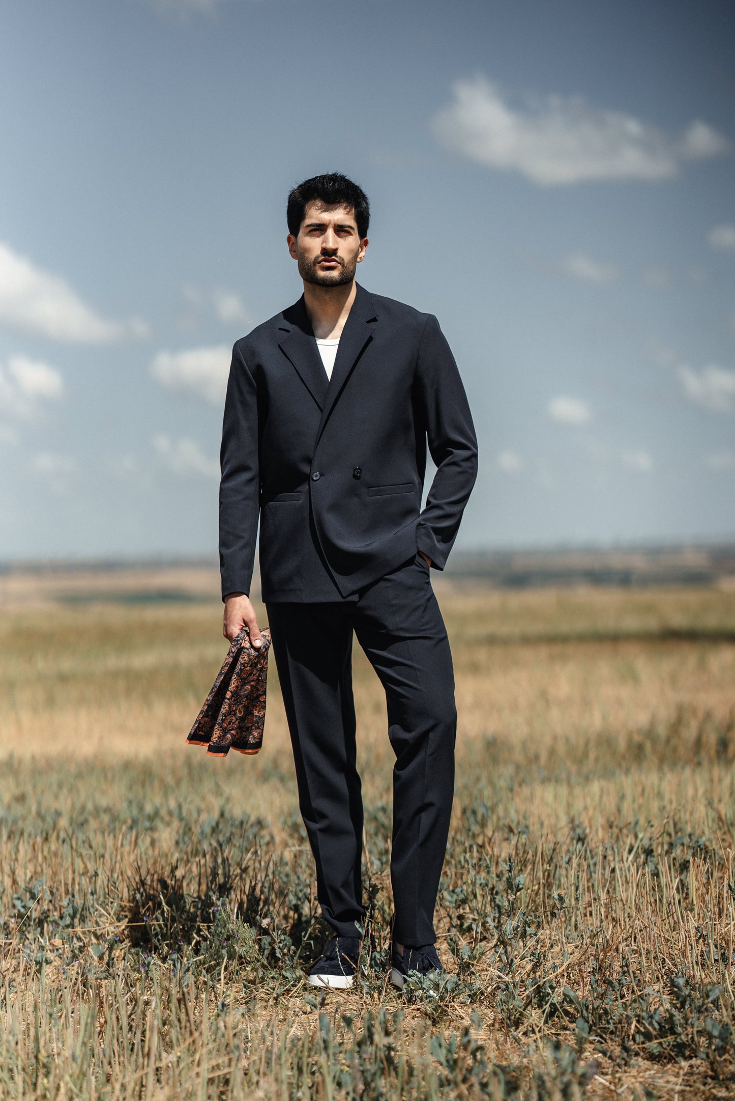 Man wearing HolloMen Cannes Navy Blue Lustrofin Blazer Suit, styled with a white shirt and navy blue loafers, set against an elegant outdoor urban backdrop.