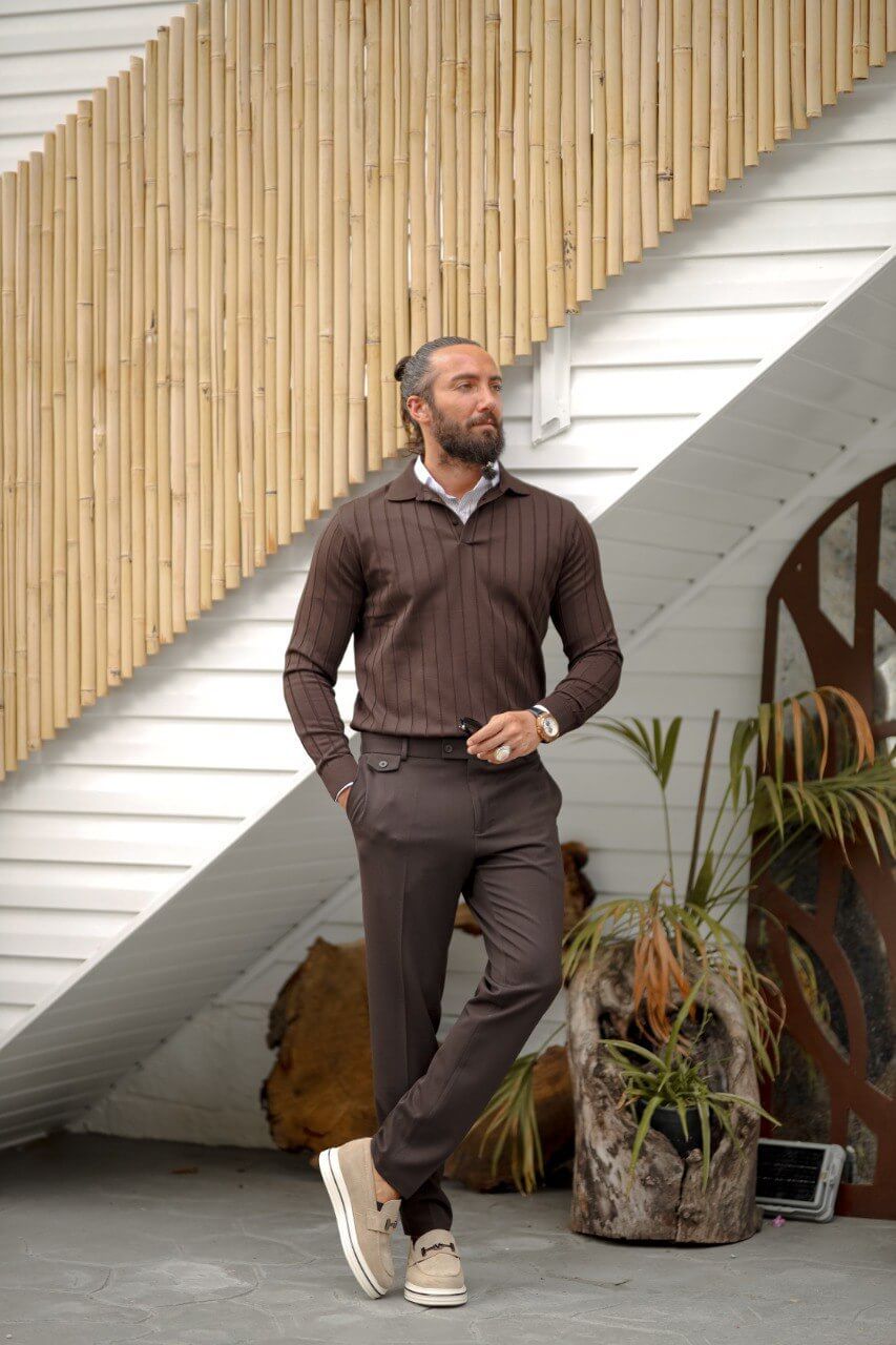 A man wearing a brown ribbed long sleeve polo knitwear with a slim fit, styled with matching brown trousers and beige loafers.