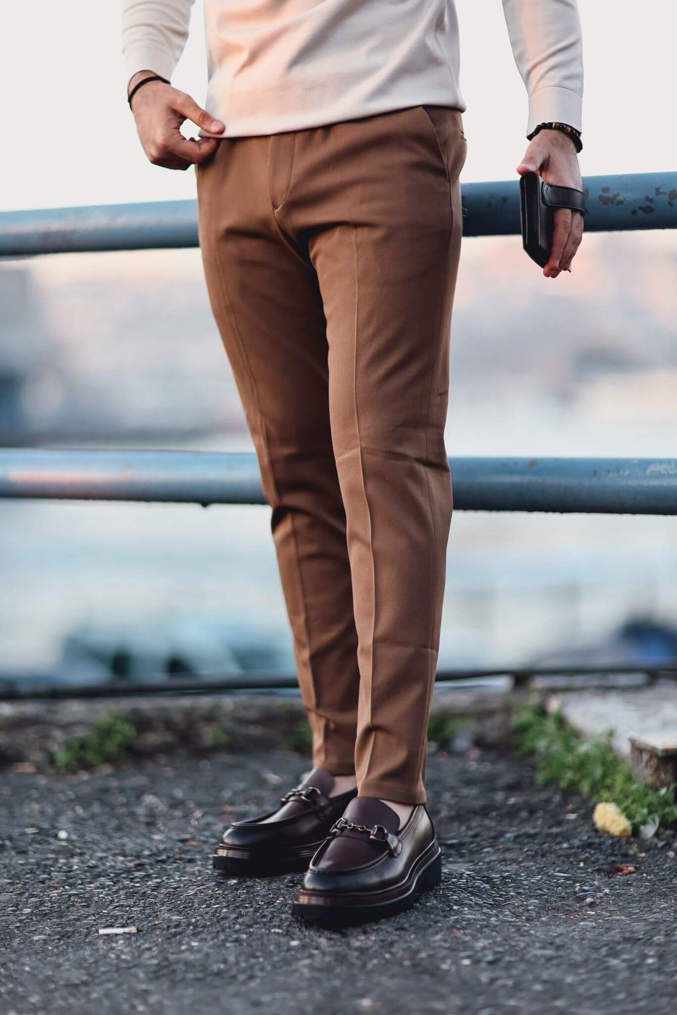 Man wearing camel slim-fit trousers styled with a checked blazer and loafers, photographed outdoors.