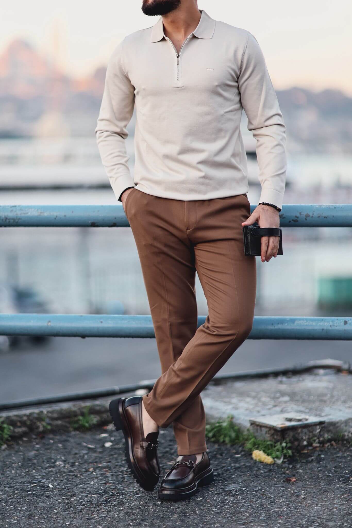 Man wearing camel slim-fit trousers styled with a checked blazer and loafers, photographed outdoors.