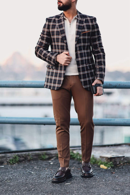 Man wearing camel slim-fit trousers styled with a checked blazer and loafers, photographed outdoors.