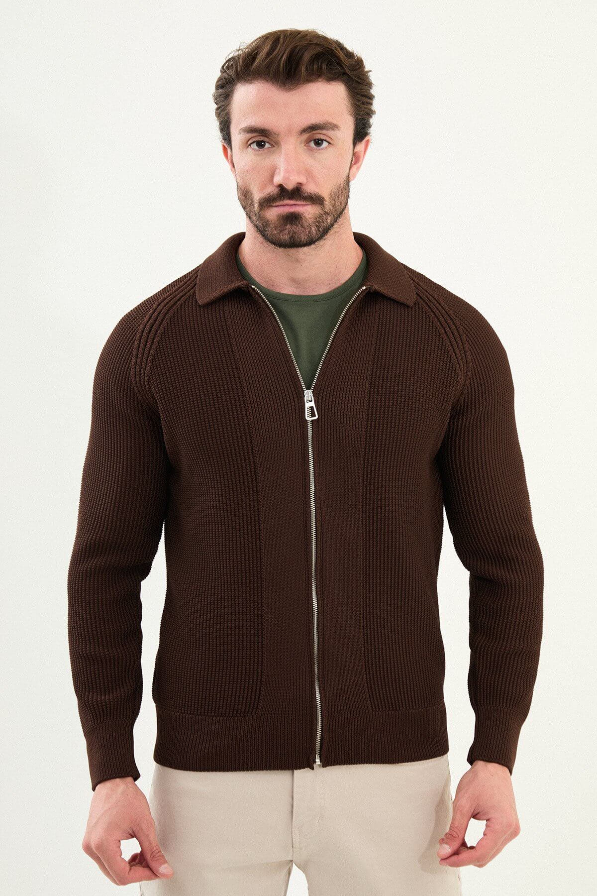 A man wearing a slim fit brown ribbed zip cardigan with a polo collar, styled with beige trousers.