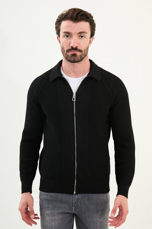 A man wearing a slim-fit black ribbed zip cardigan with a polo collar, styled with a white T-shirt and grey jeans.