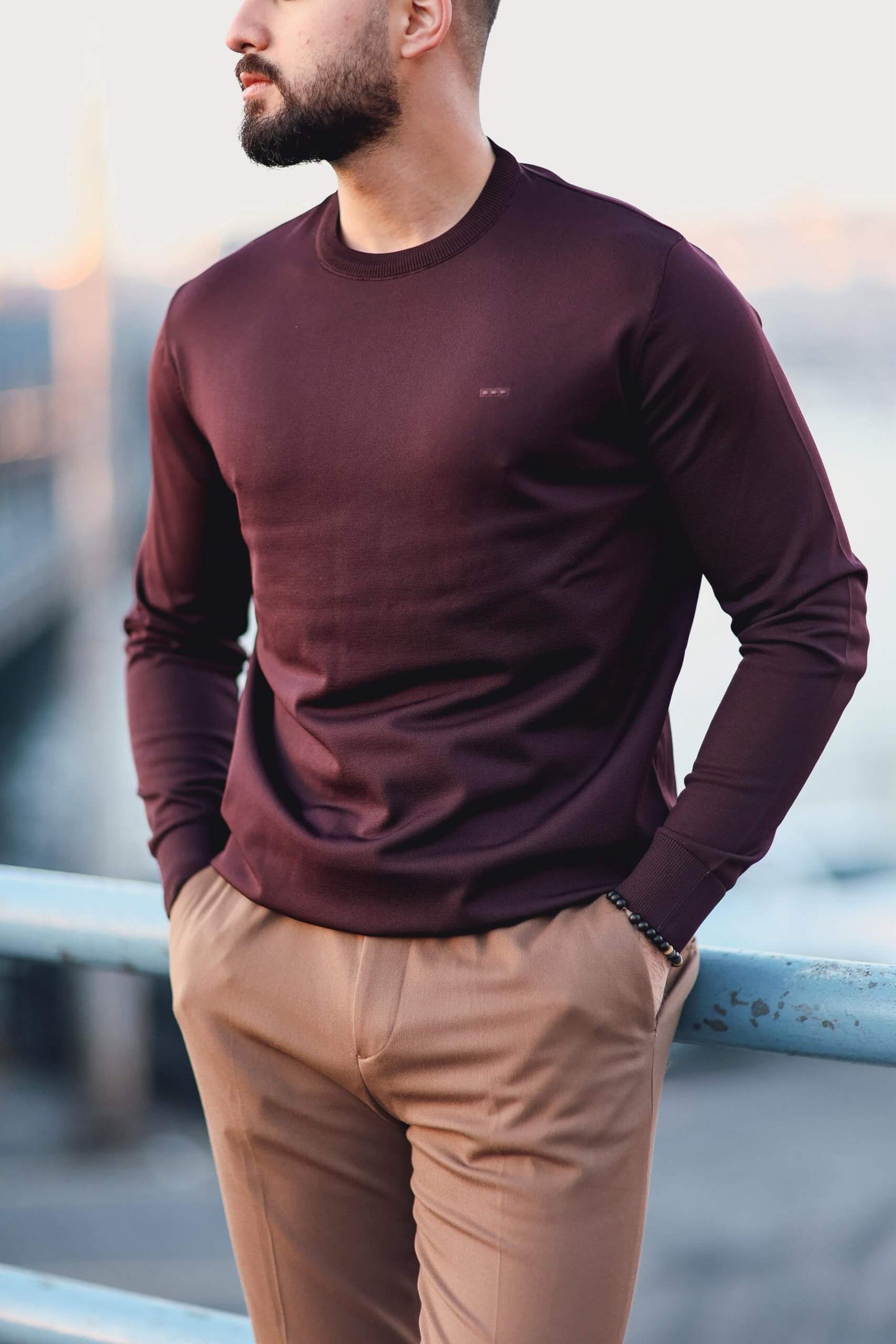 Men’s cherry long-sleeve knit sweatshirt styled with camel trousers outdoors