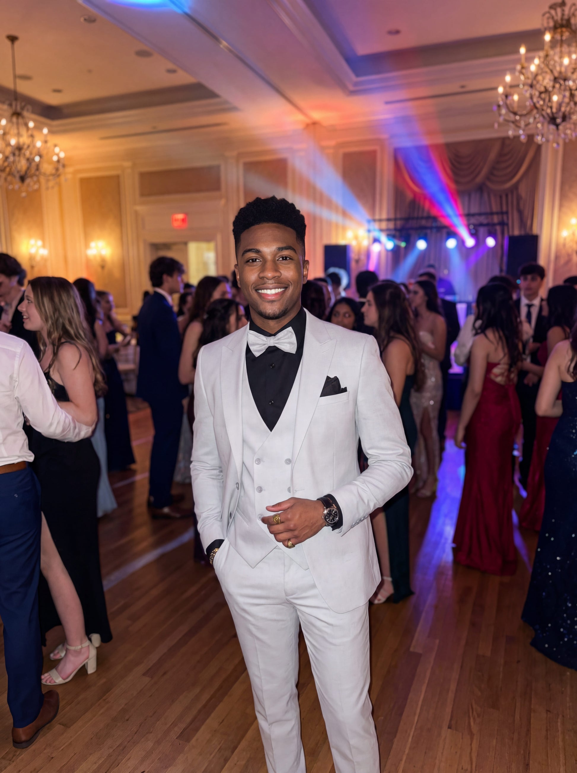 Young man wearing HolloMen's Gray Tuxedo Suit for prom, standing outdoors in a modern setting, featuring a black shirt and a stylish bow tie, showcasing a sleek and sophisticated look.