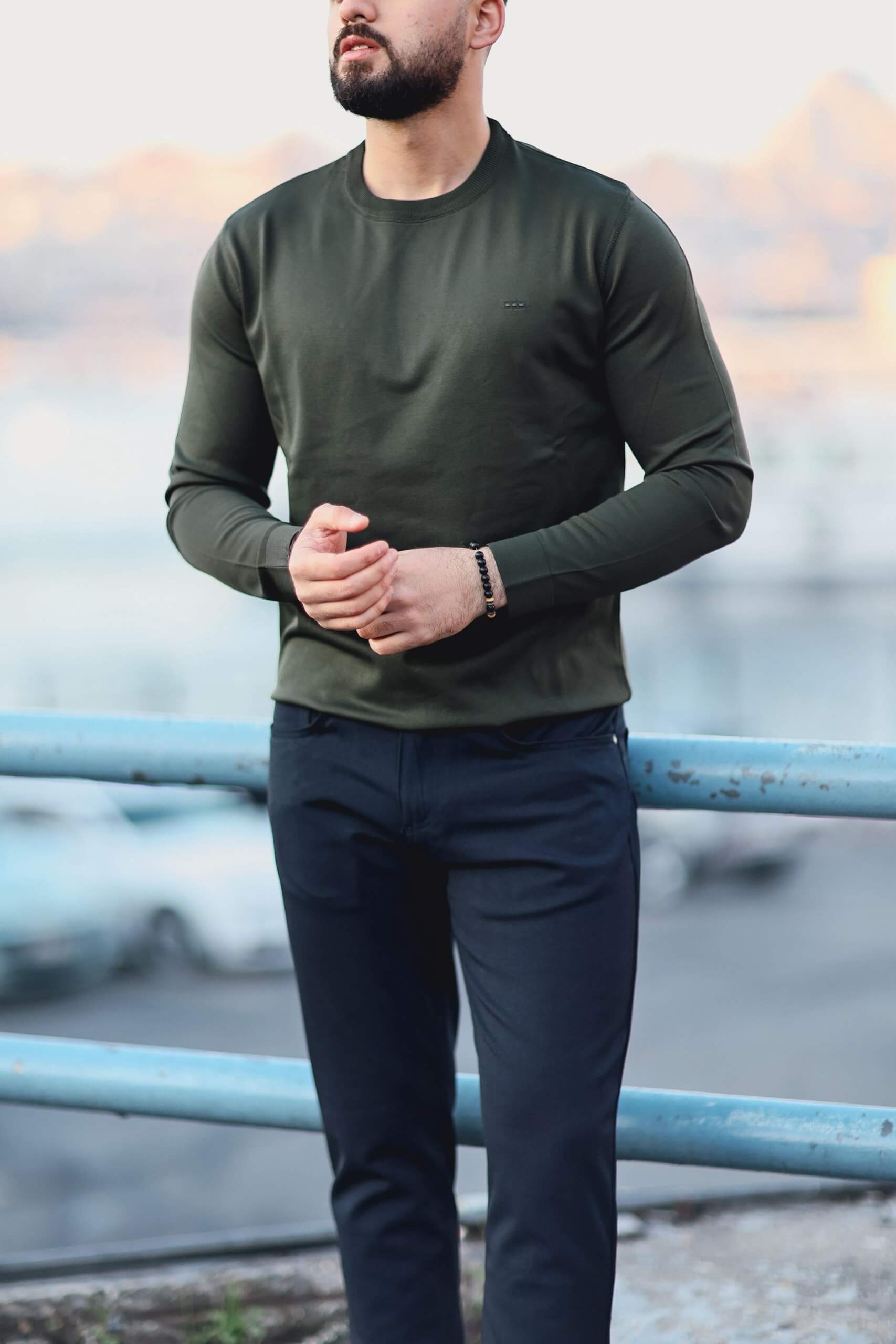 Men’s green long-sleeve cotton-blend polo sweater worn outdoors, showcasing fitted design and ribbed collar