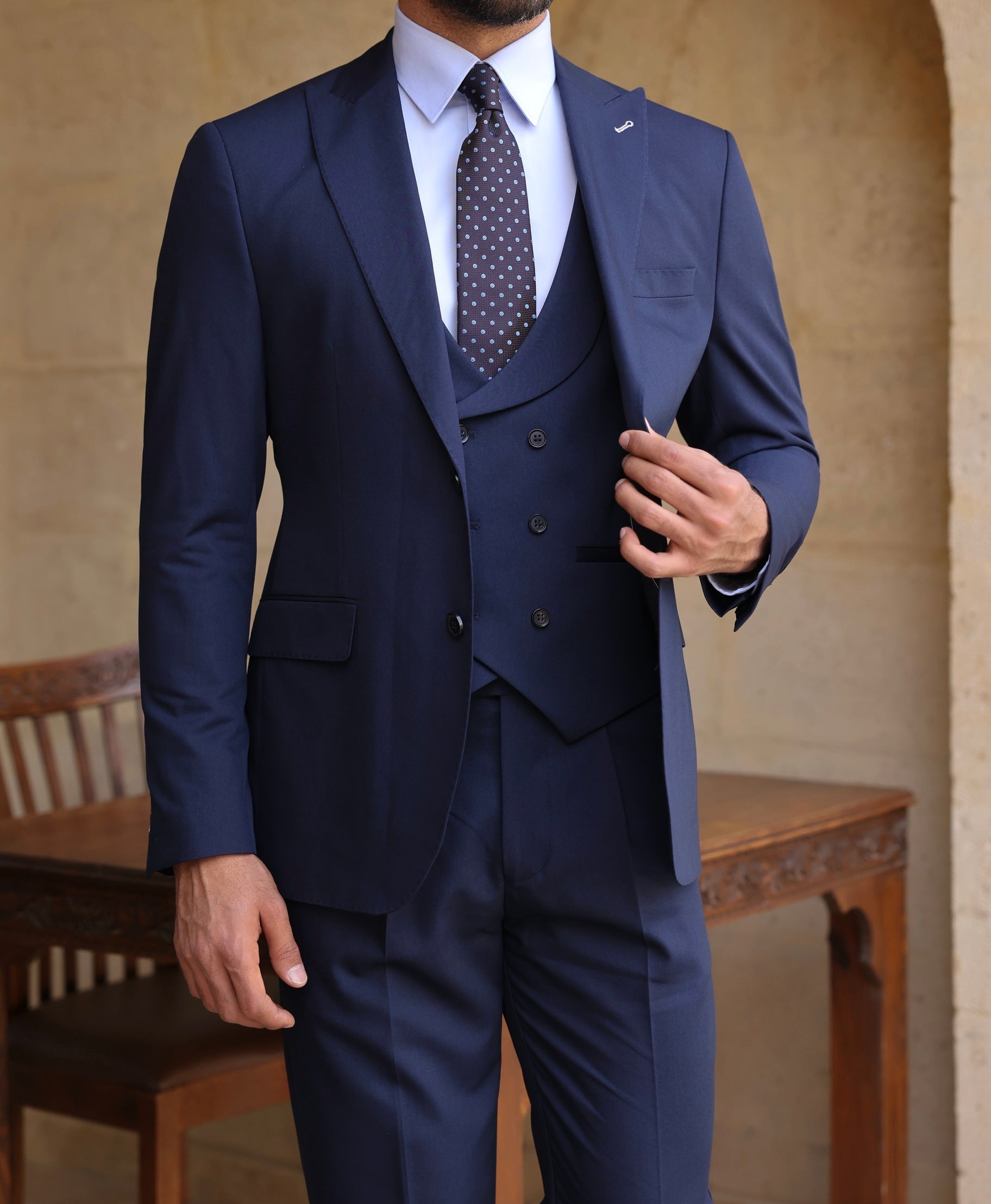 Men’s navy modern-fit 3-piece suit with blazer, waistcoat, and trousers, styled with a white shirt and patterned tie for a clean, elegant look.
