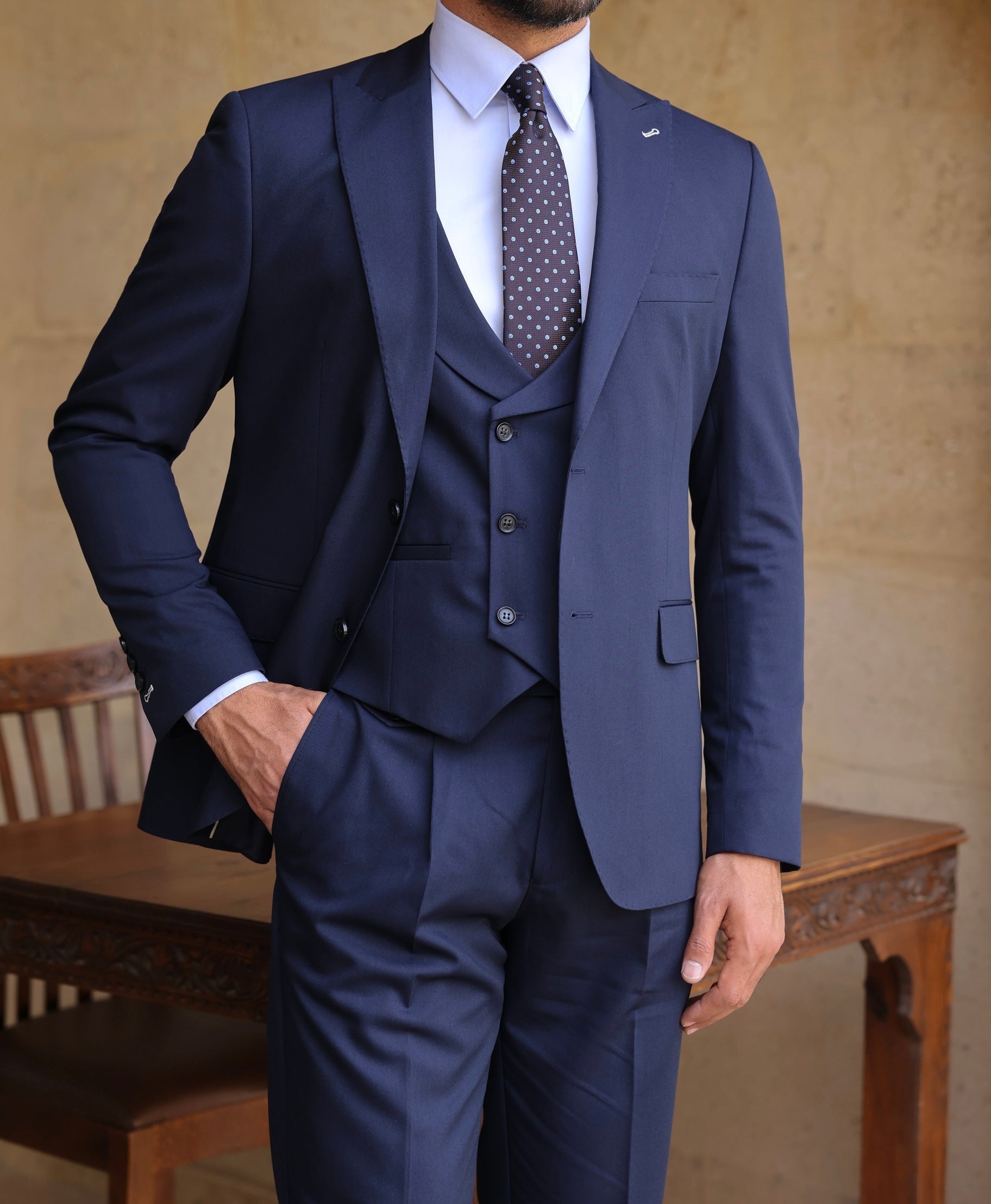 Men’s navy modern-fit 3-piece suit with blazer, waistcoat, and trousers, styled with a white shirt and patterned tie for a clean, elegant look.