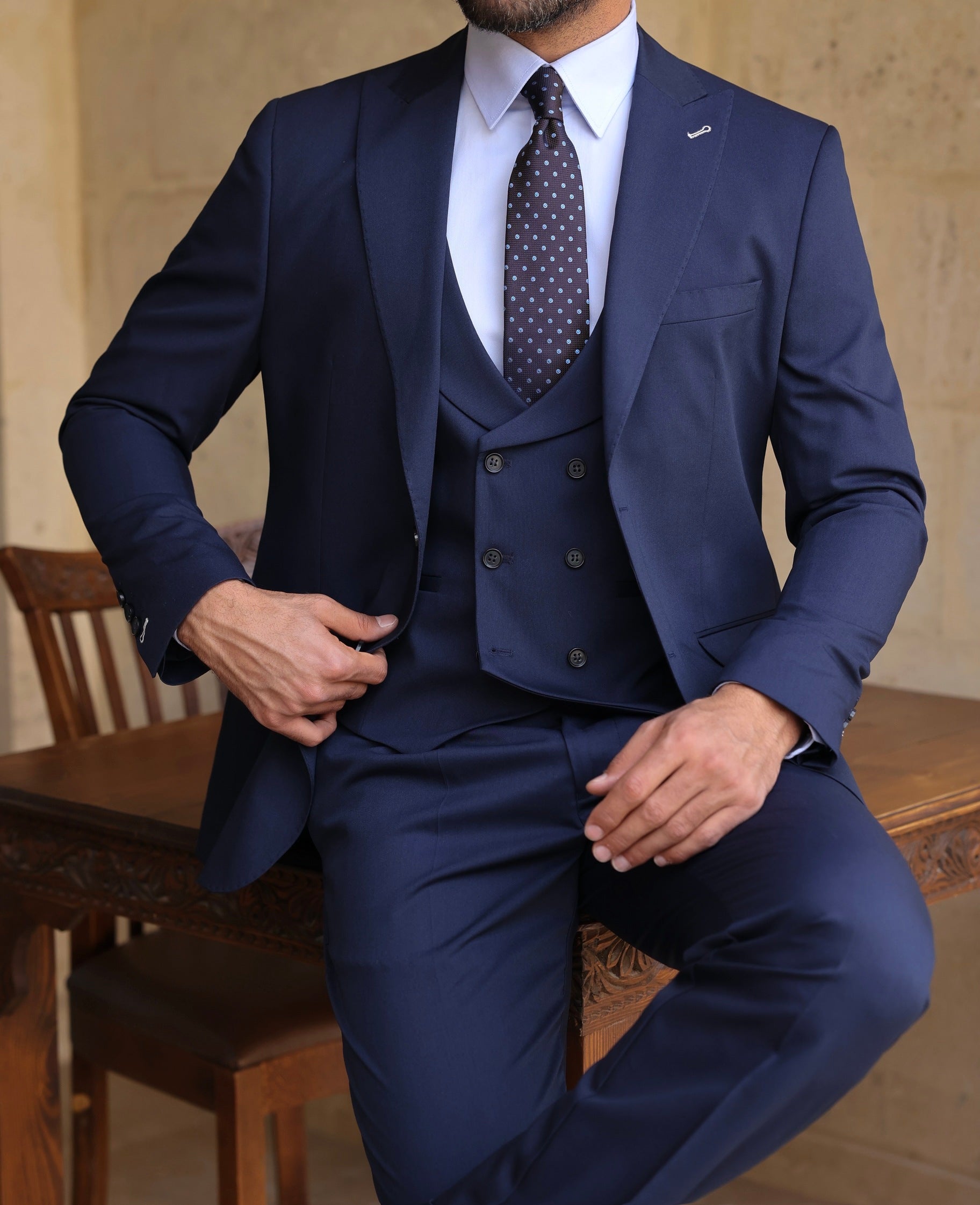Men’s navy modern-fit 3-piece suit with blazer, waistcoat, and trousers, styled with a white shirt and patterned tie for a clean, elegant look.
