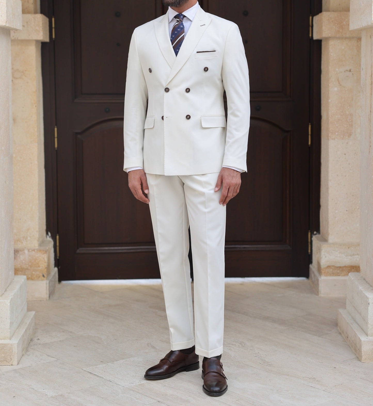 Men’s white double-breasted slim-fit suit with tailored trousers, styled with a dress shirt and tie for a clean, modern formal look.