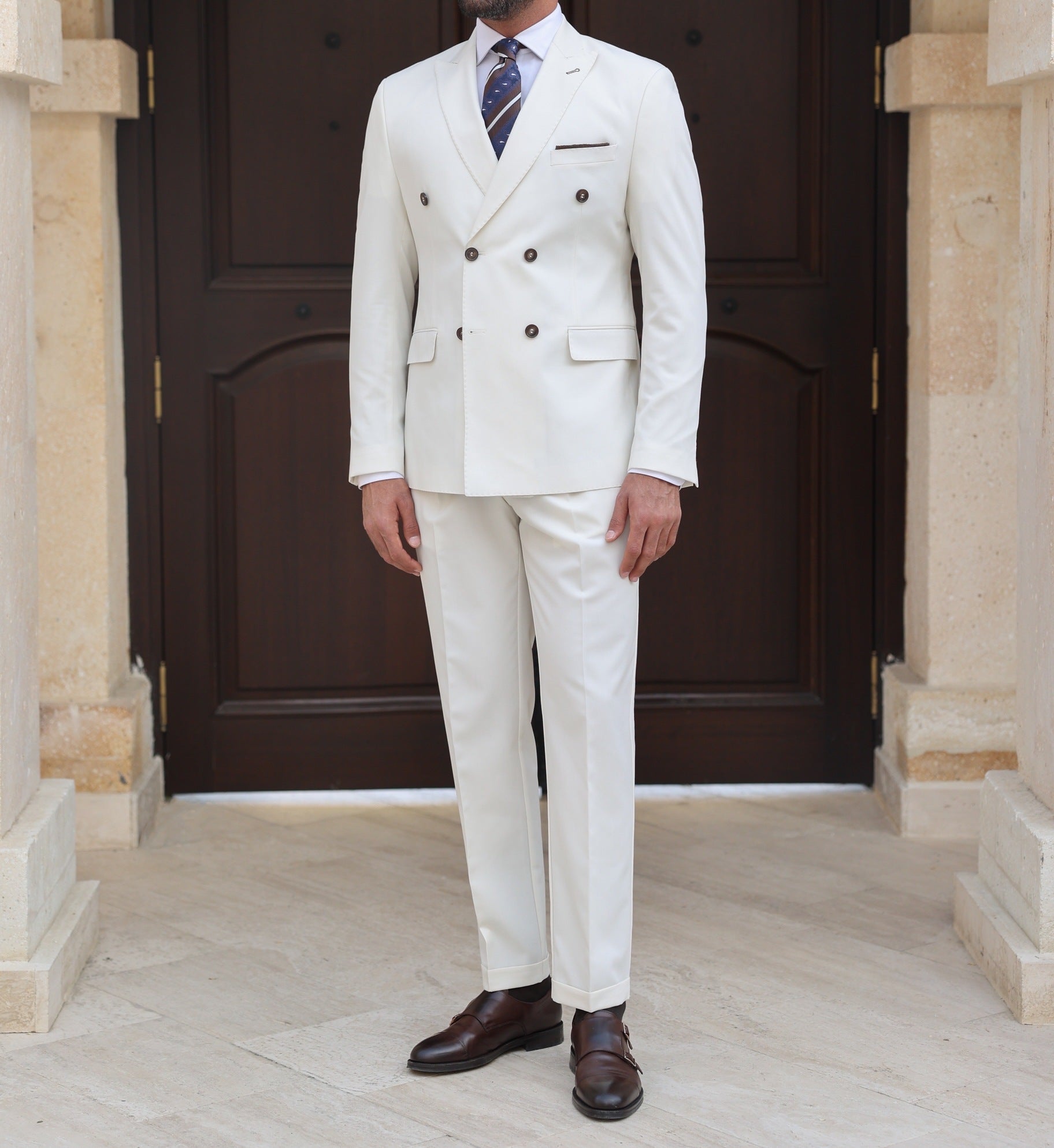 Men’s white double-breasted slim-fit suit with tailored trousers, styled with a dress shirt and tie for a clean, modern formal look.