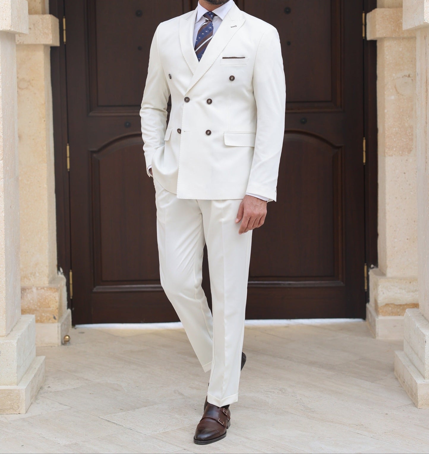Men’s white double-breasted slim-fit suit with tailored trousers, styled with a dress shirt and tie for a clean, modern formal look.