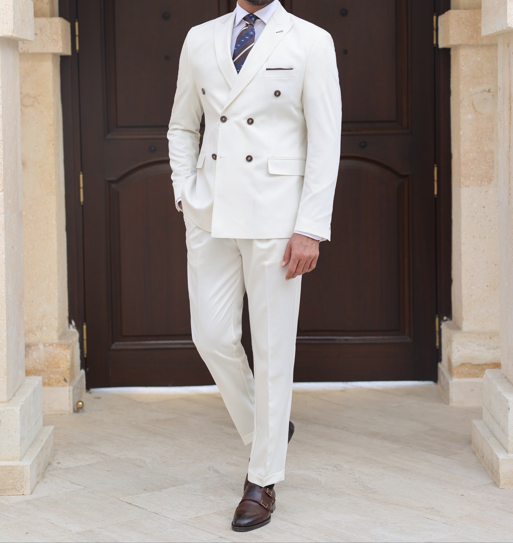 Men’s white double-breasted slim-fit suit with tailored trousers, styled with a dress shirt and tie for a clean, modern formal look.