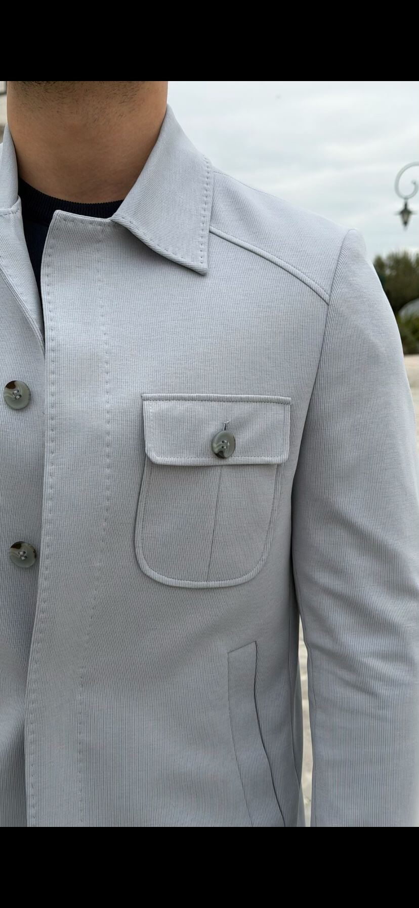 Men’s ice blue shirt jacket with flap pockets styled with black outfit and white sneakers in a modern smart casual look