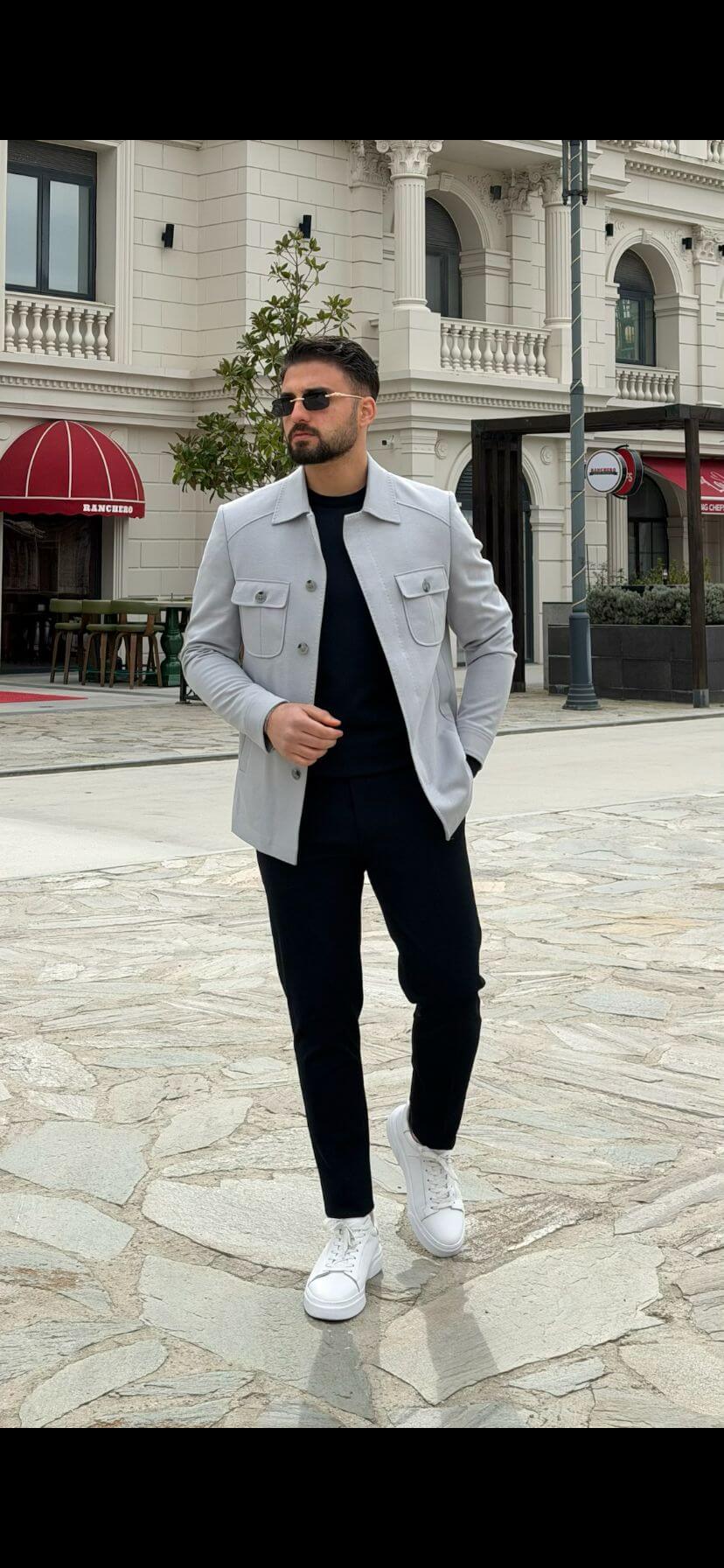 Men’s ice blue shirt jacket with flap pockets styled with black outfit and white sneakers in a modern smart casual look