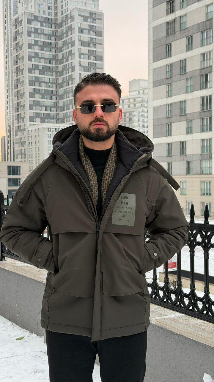 Men’s matte khaki technical winter parka with storm hood and reinforced chin guard, wind-resistant water-repellent polyester shell with stretch, oversized flap pockets and adjustable cuffs, urban commuter outerwear.