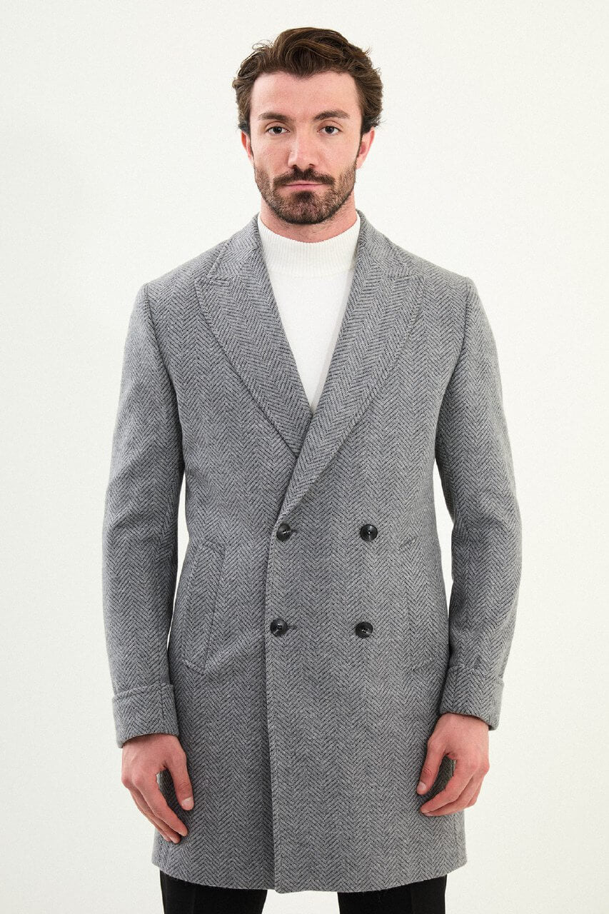 Full-body view of a man in a gray double-breasted slim fit coat, styled with black trousers and black leather boots.