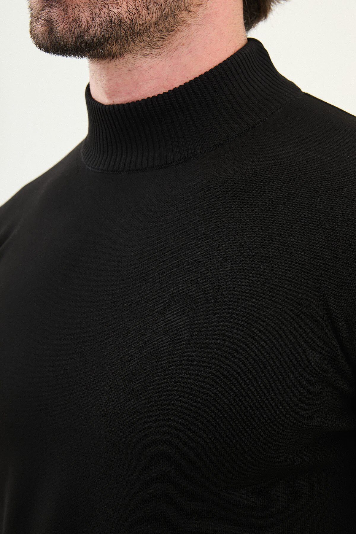 A men’s slim fit black half-turtleneck sweater with long sleeves, styled for the fall-winter season.