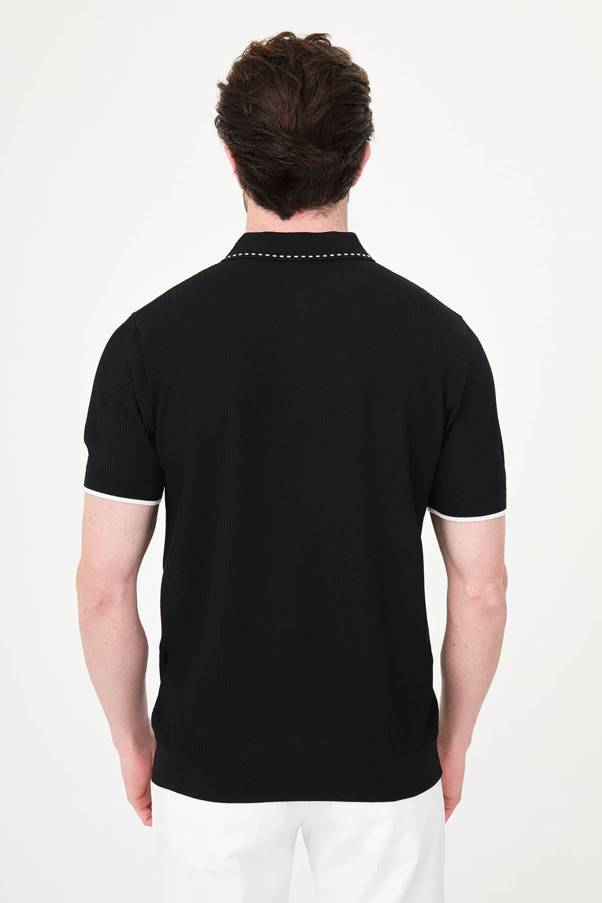 Man wearing black slim-fit quarter-zip polo t-shirt with white stripe accents, styled with white trousers.
