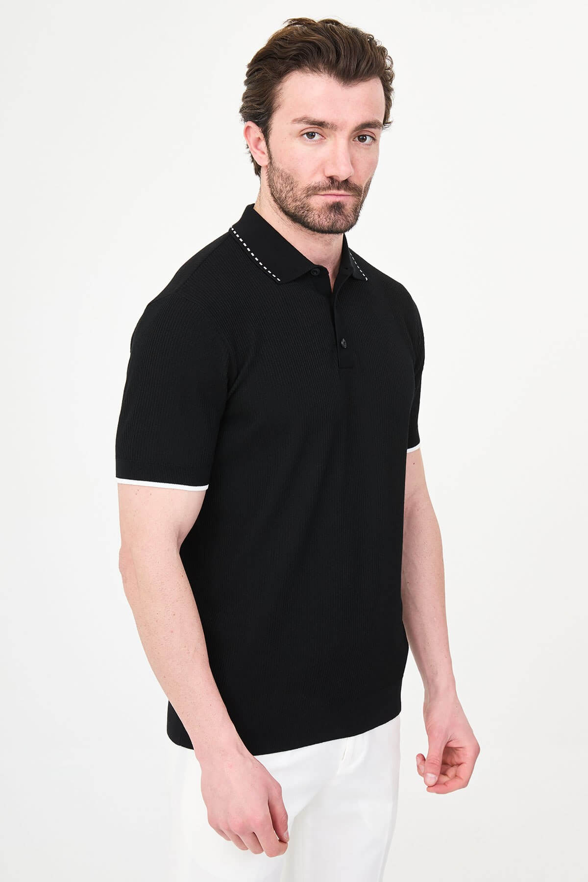 Man wearing black slim-fit quarter-zip polo t-shirt with white stripe accents, styled with white trousers.