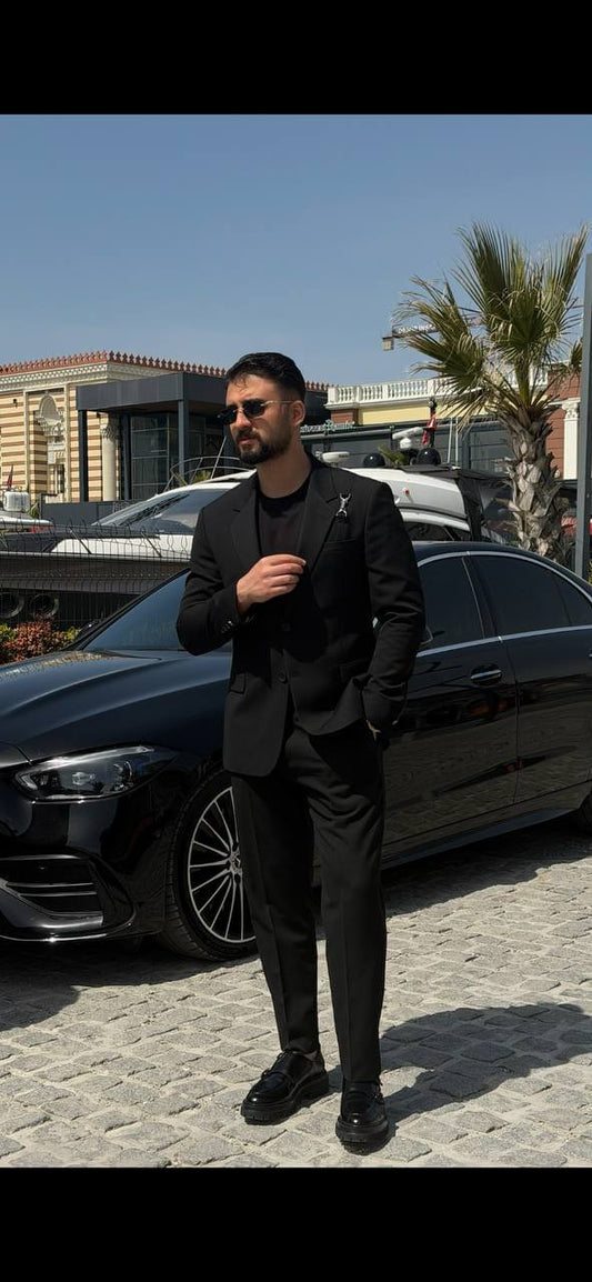 Men’s black slim fit suit with structured tailoring and harness detail, modern formal outfit styled with black shoes and minimal design