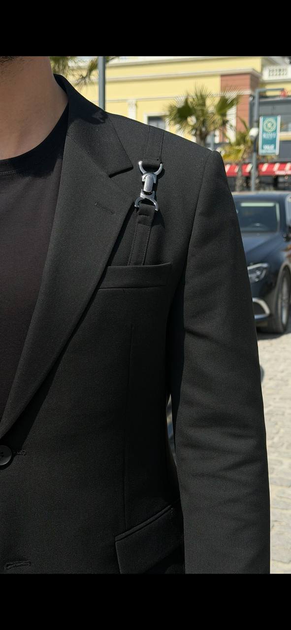 Men’s black slim fit suit with structured tailoring and harness detail, modern formal outfit styled with black shoes and minimal design